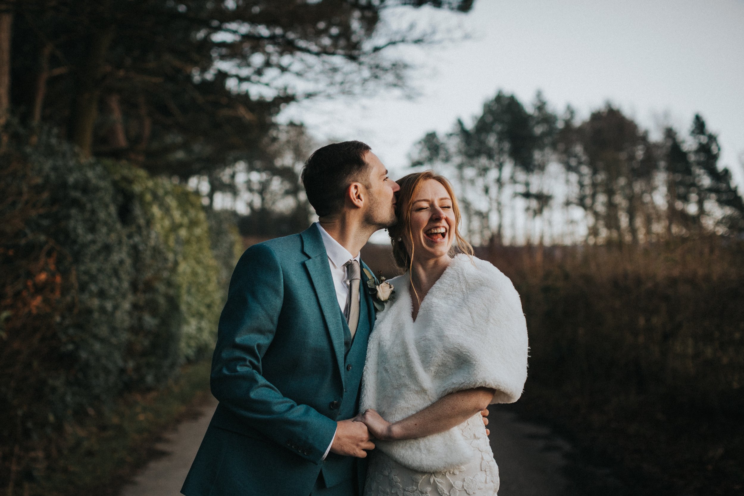 Bride looking joyful as Groom kisses her. 