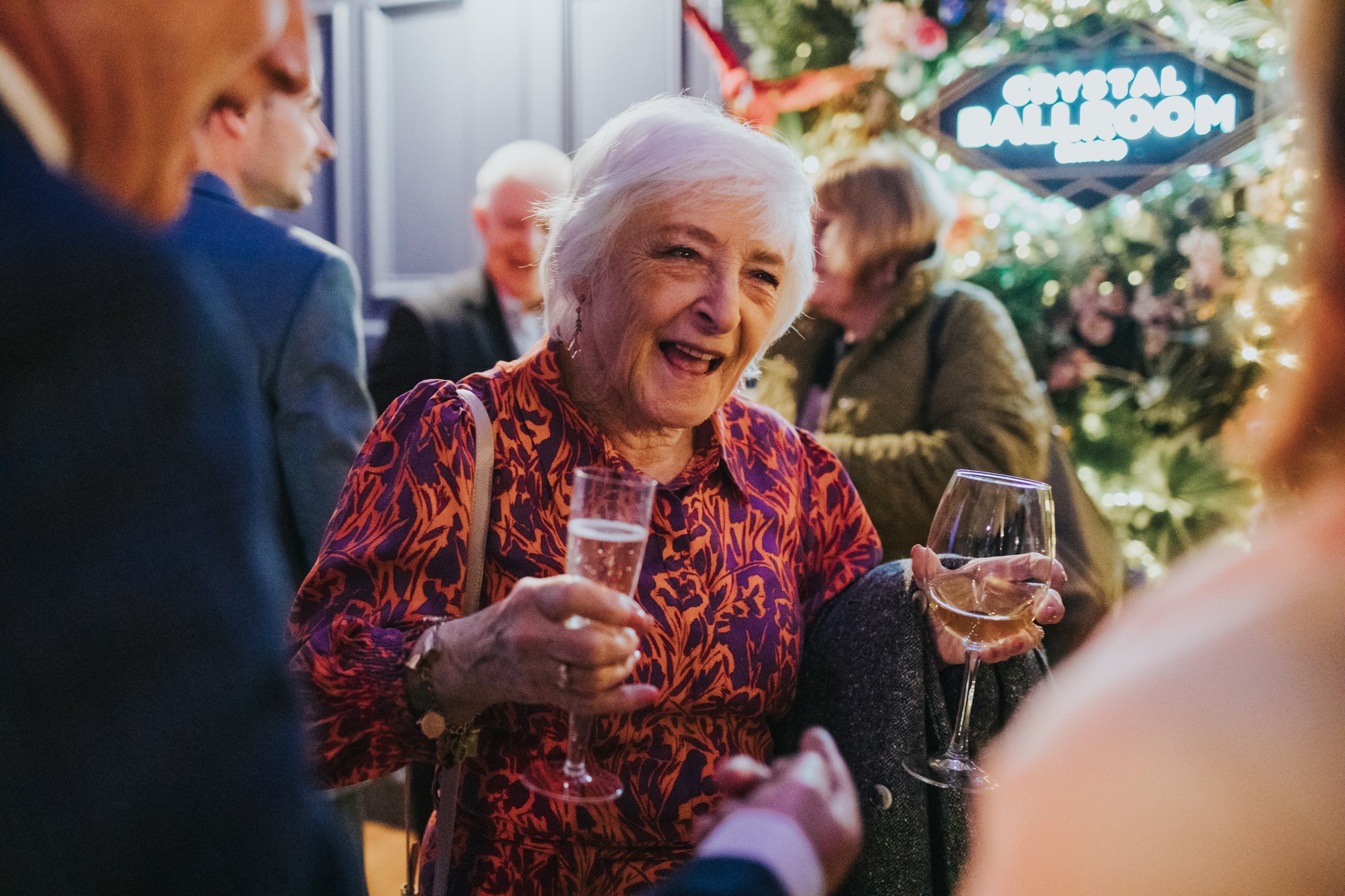 Grandmother smiling holding two drinks. 