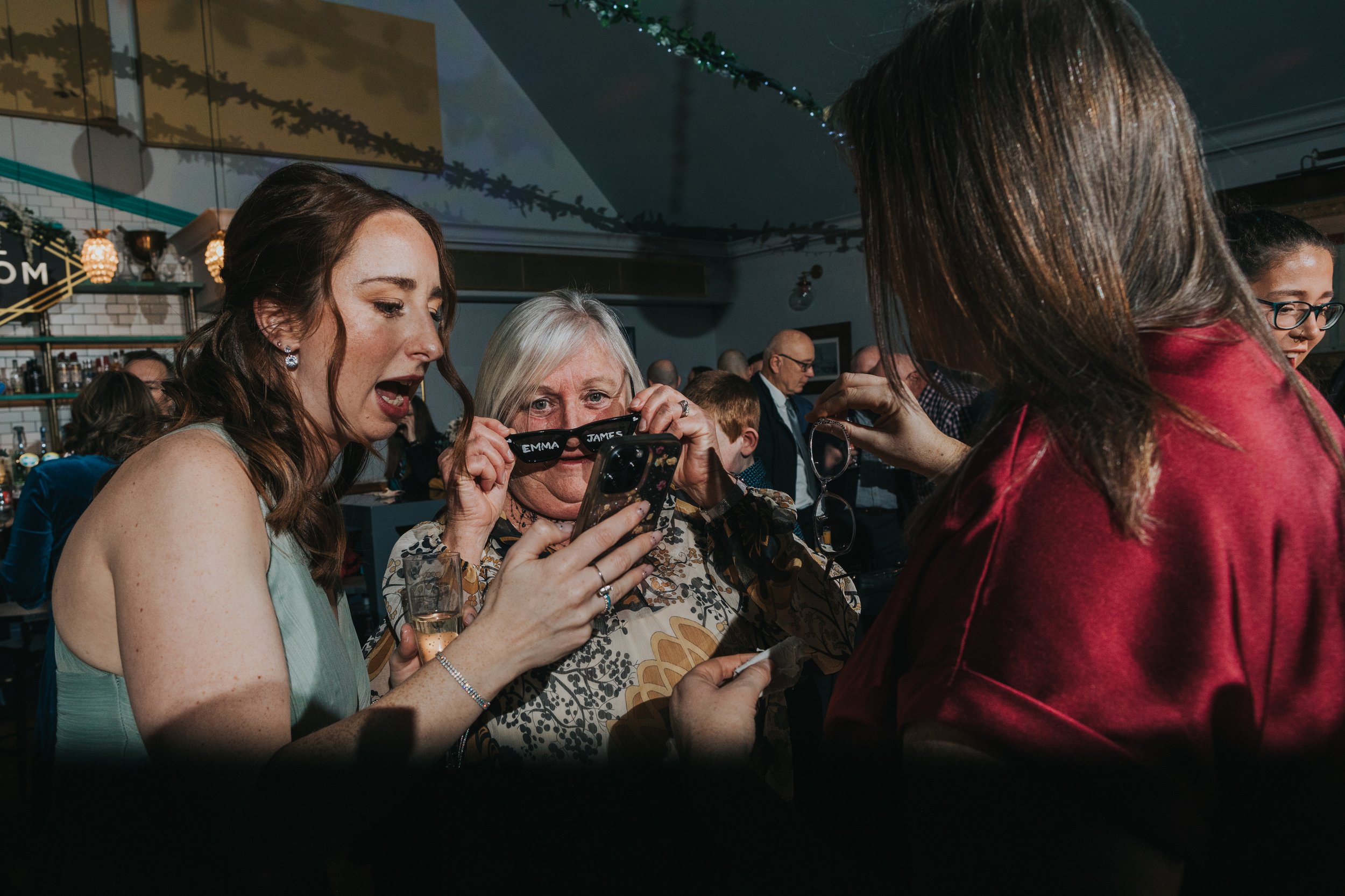 Guests posing with Emma and James glasses for photos.