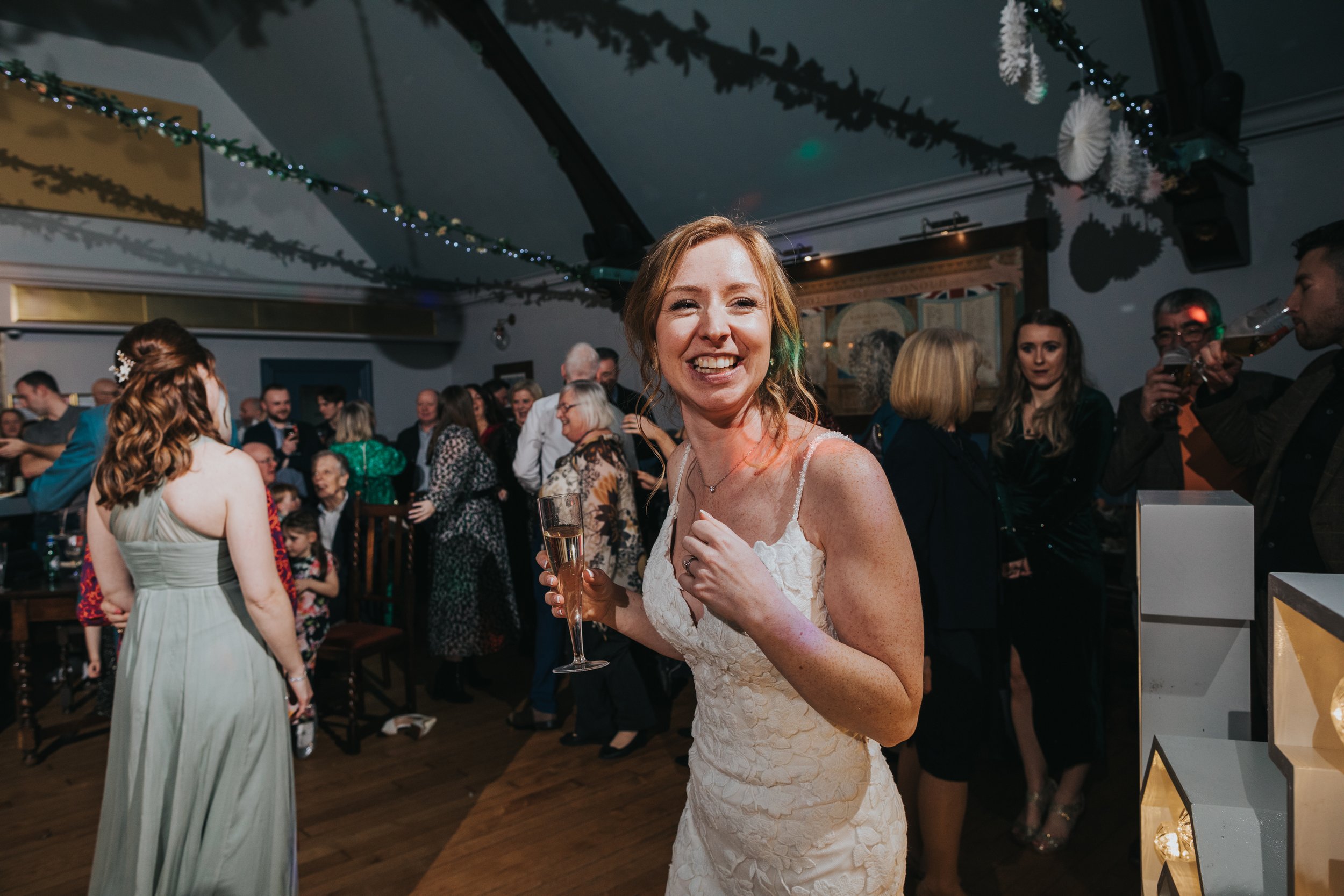 Bride laughing on the dance floor surrounded by friends and family. 