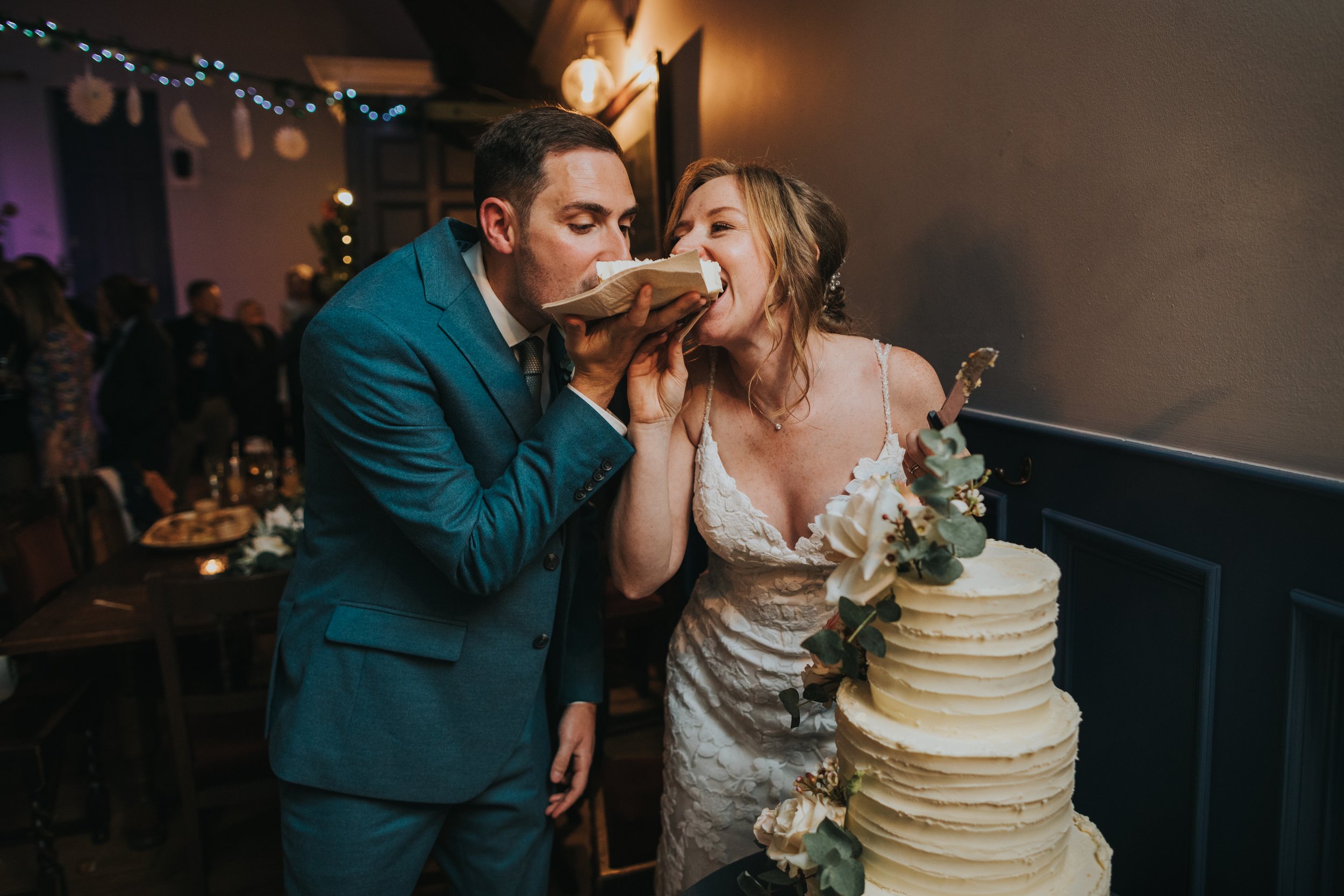 Couple bite into a peice of wedding cake together. 