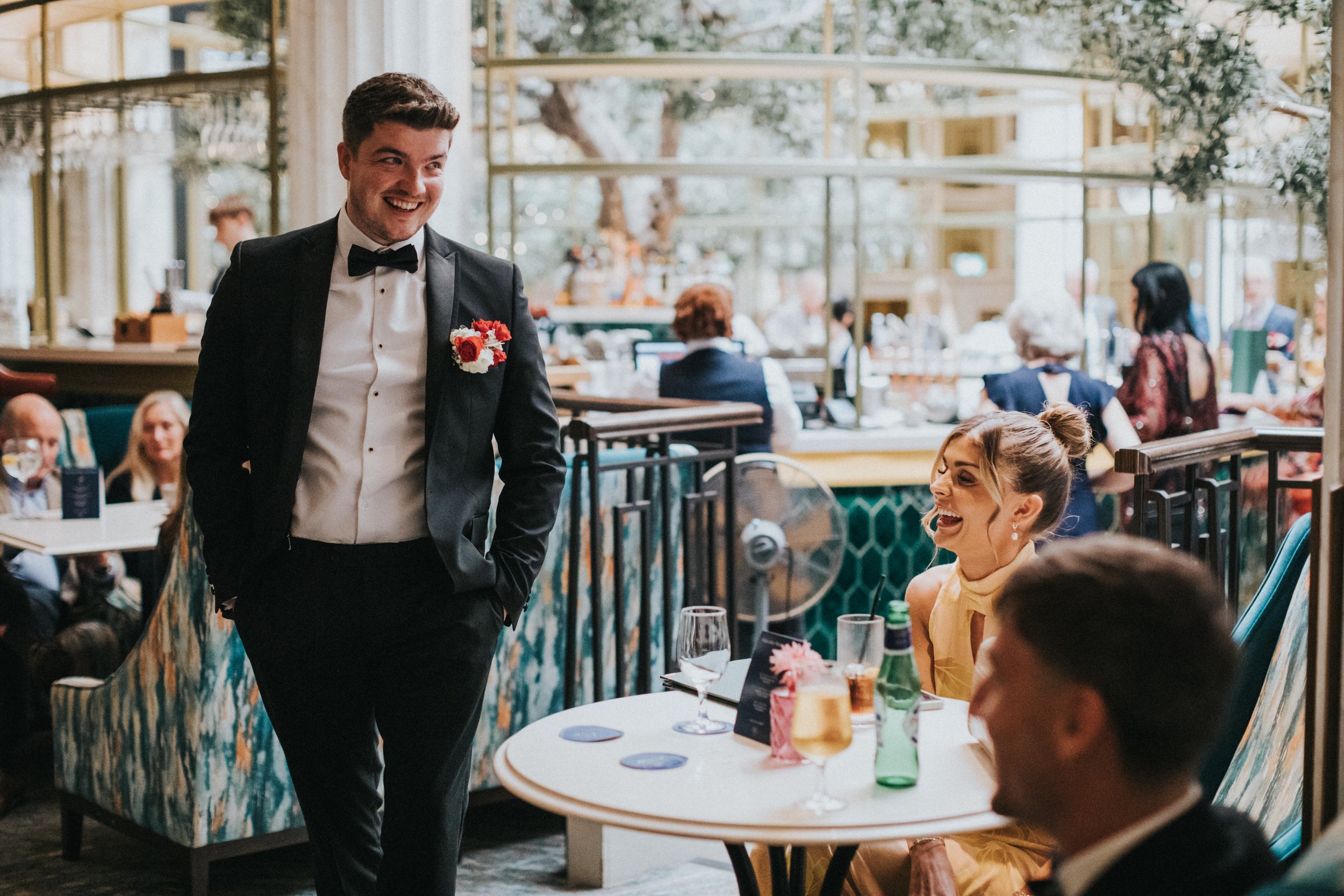 Groom laughs with wedding guests in the Midland Hotel Bar.