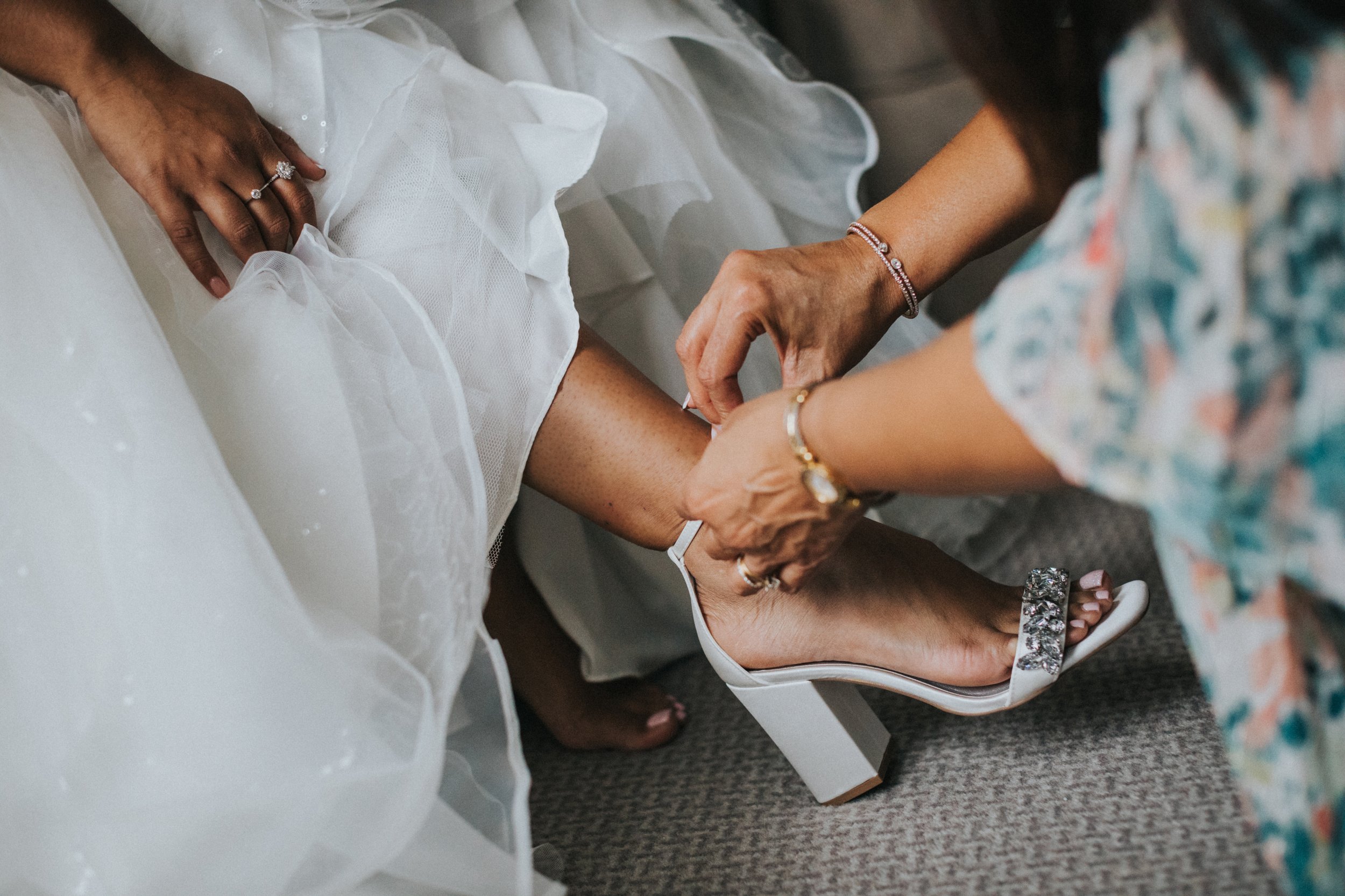 Mother helps Bride put on her wedding shoes. 