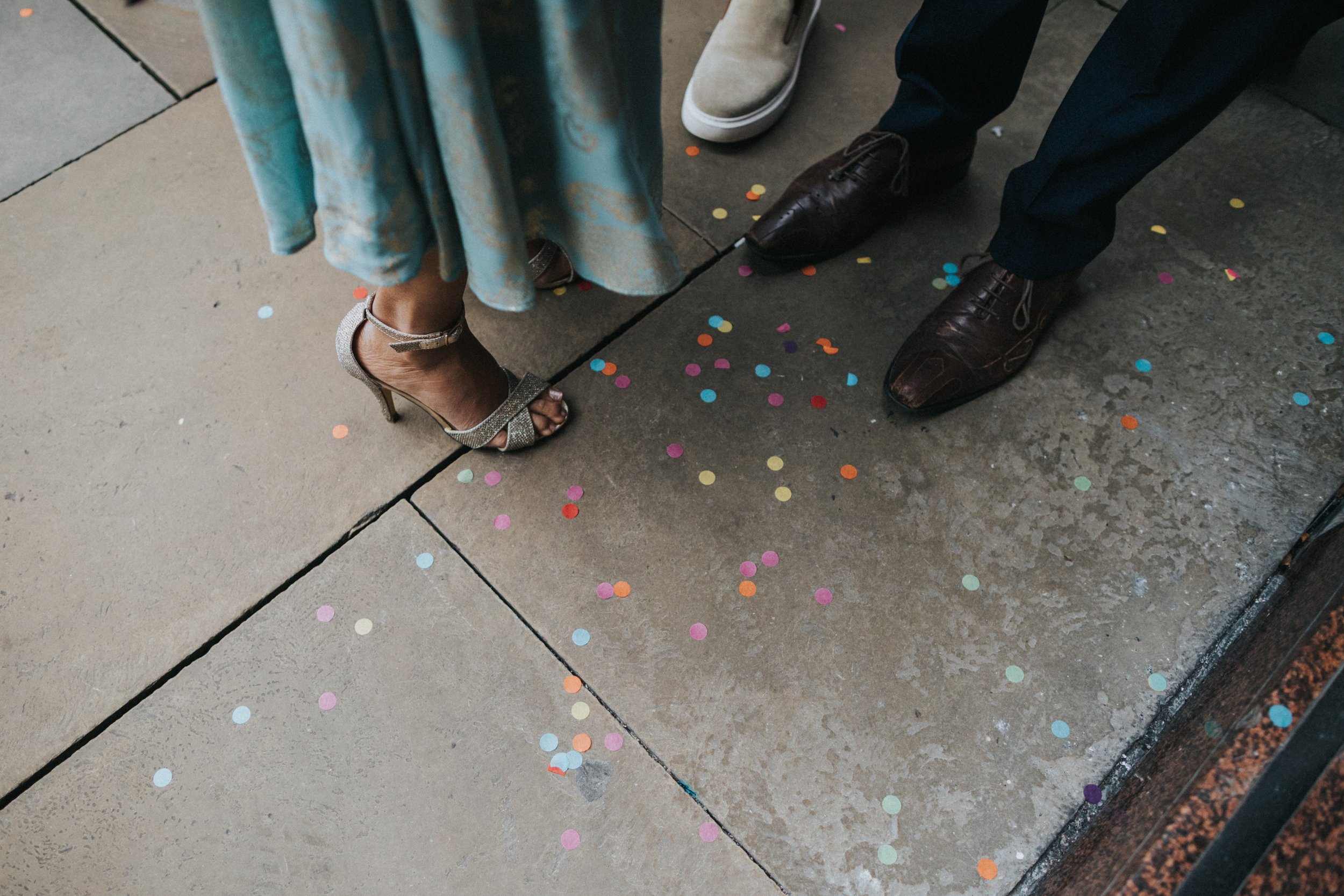 Lady with blue dress and silvers shoes has spilt colourful confetti on the floor.  