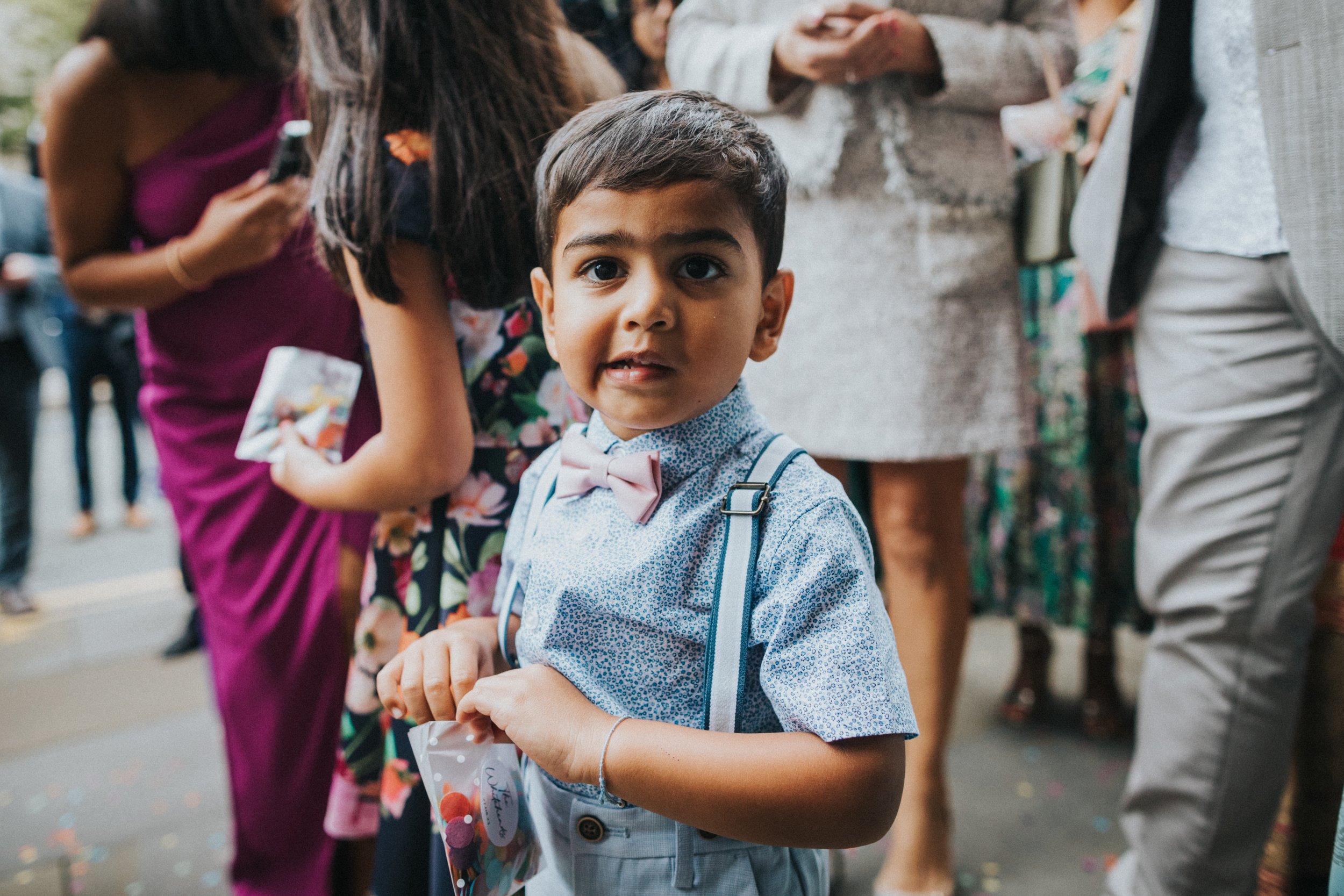 Little boy wearing a blue shirt waits with confetti. 