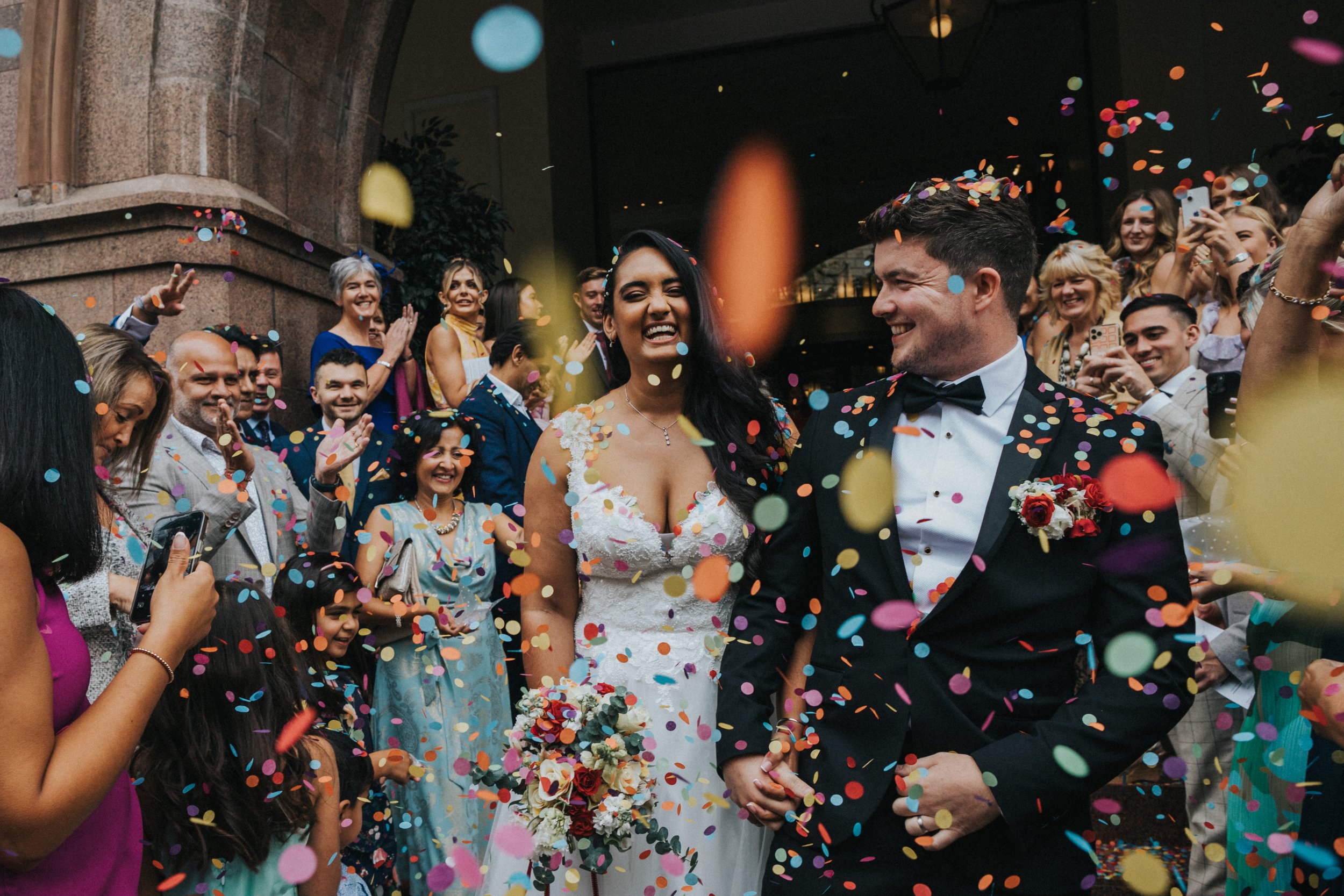 Bride and Groom are engulfed with confetti on thier wedding day at the Midland Hotel, Manchester. 