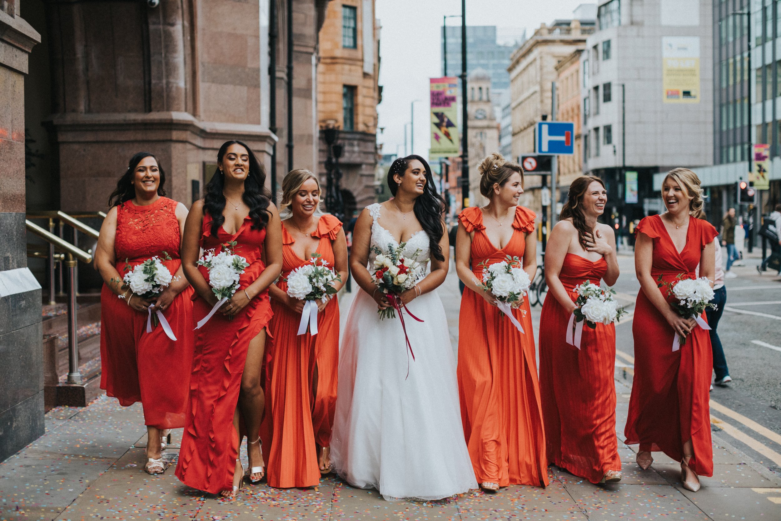 Bride and Bridesmaids walk down the street together. 