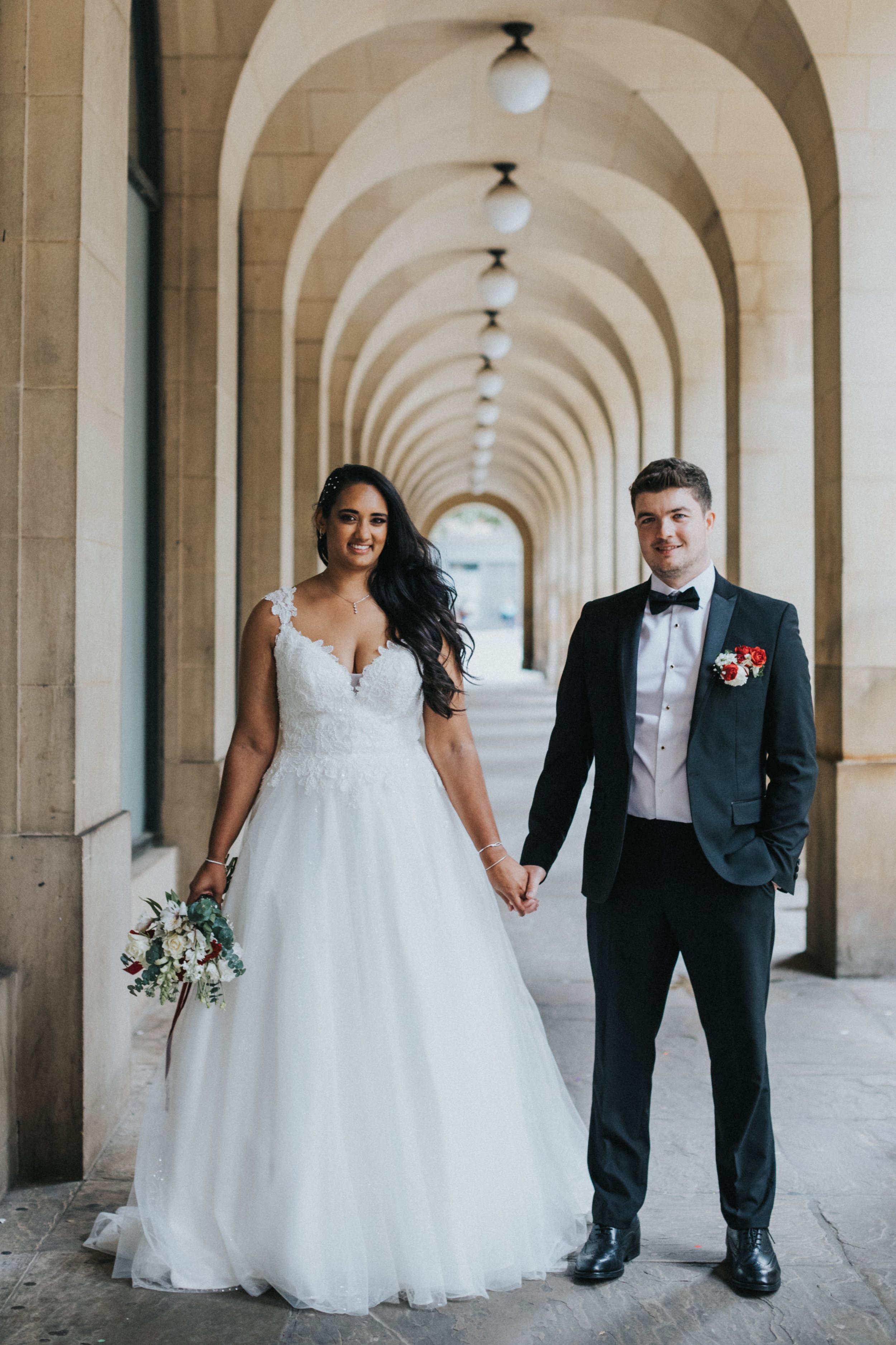 Bride and Groom Stand for a photo under the arches by Manchester Town Hall. 