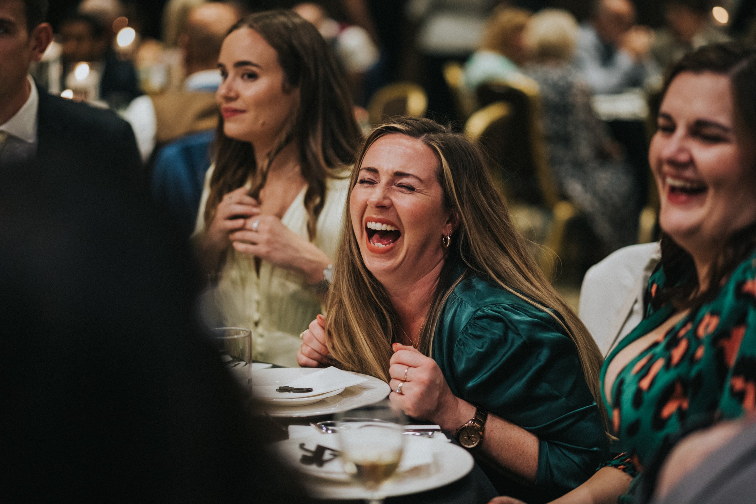 Female wedding guest dressed in green laughing. 