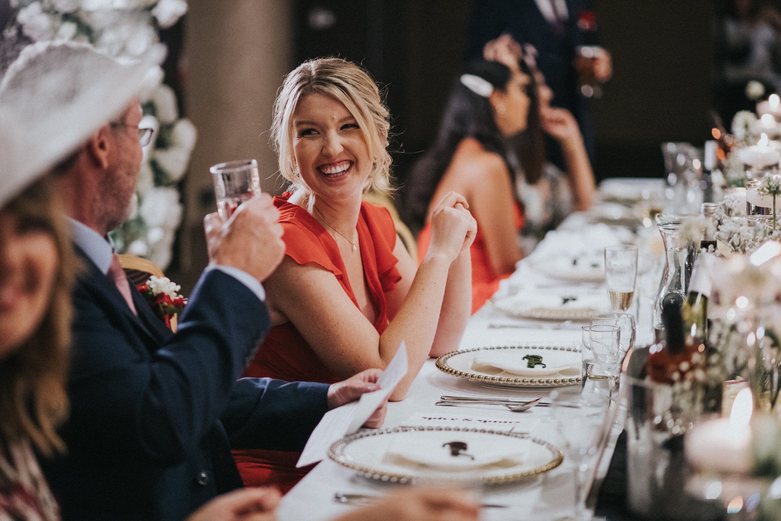 Grooms Sister sits laughing at her Dad. 