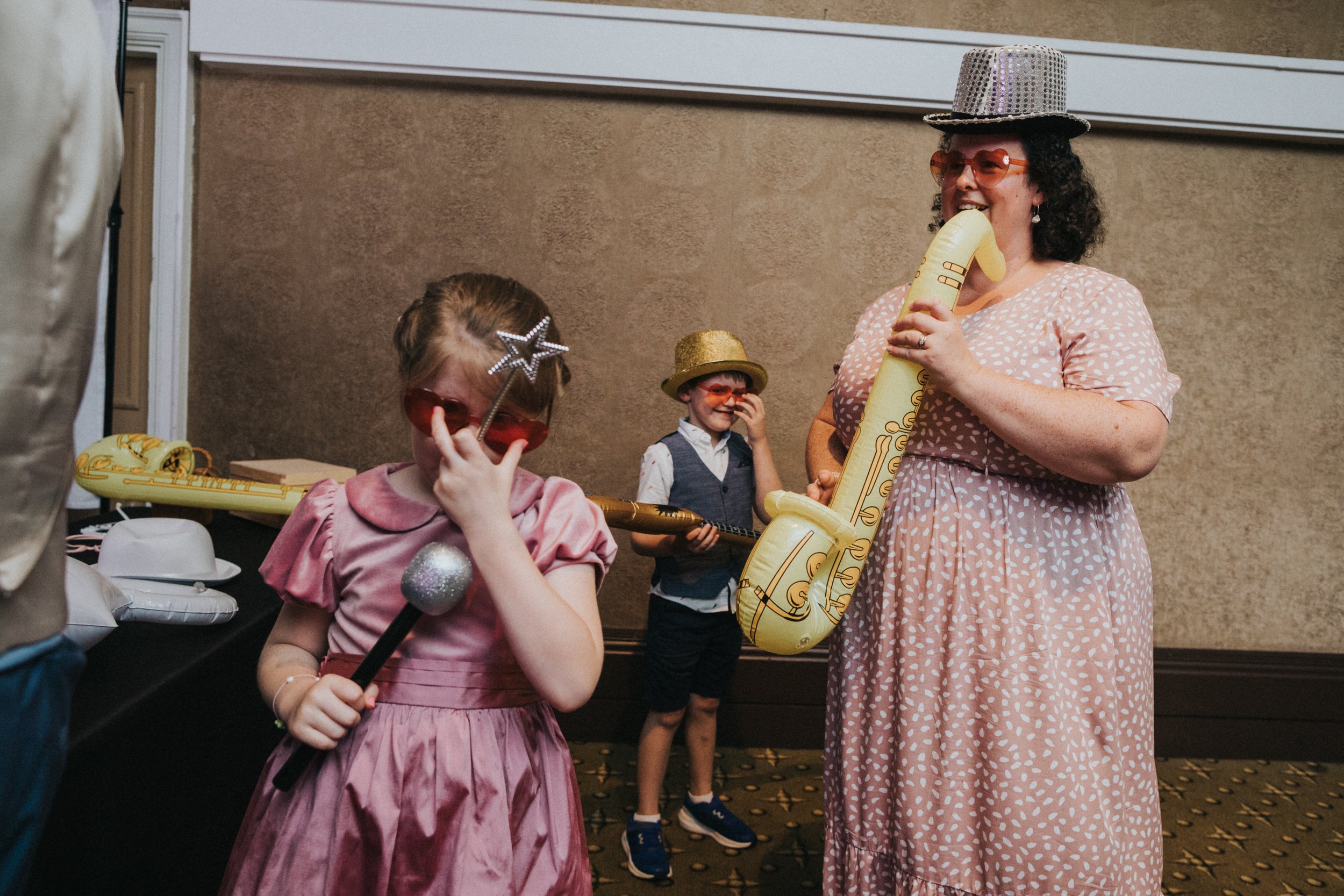 Family poses with blow up saxophone and photo booth hats and glasses. 