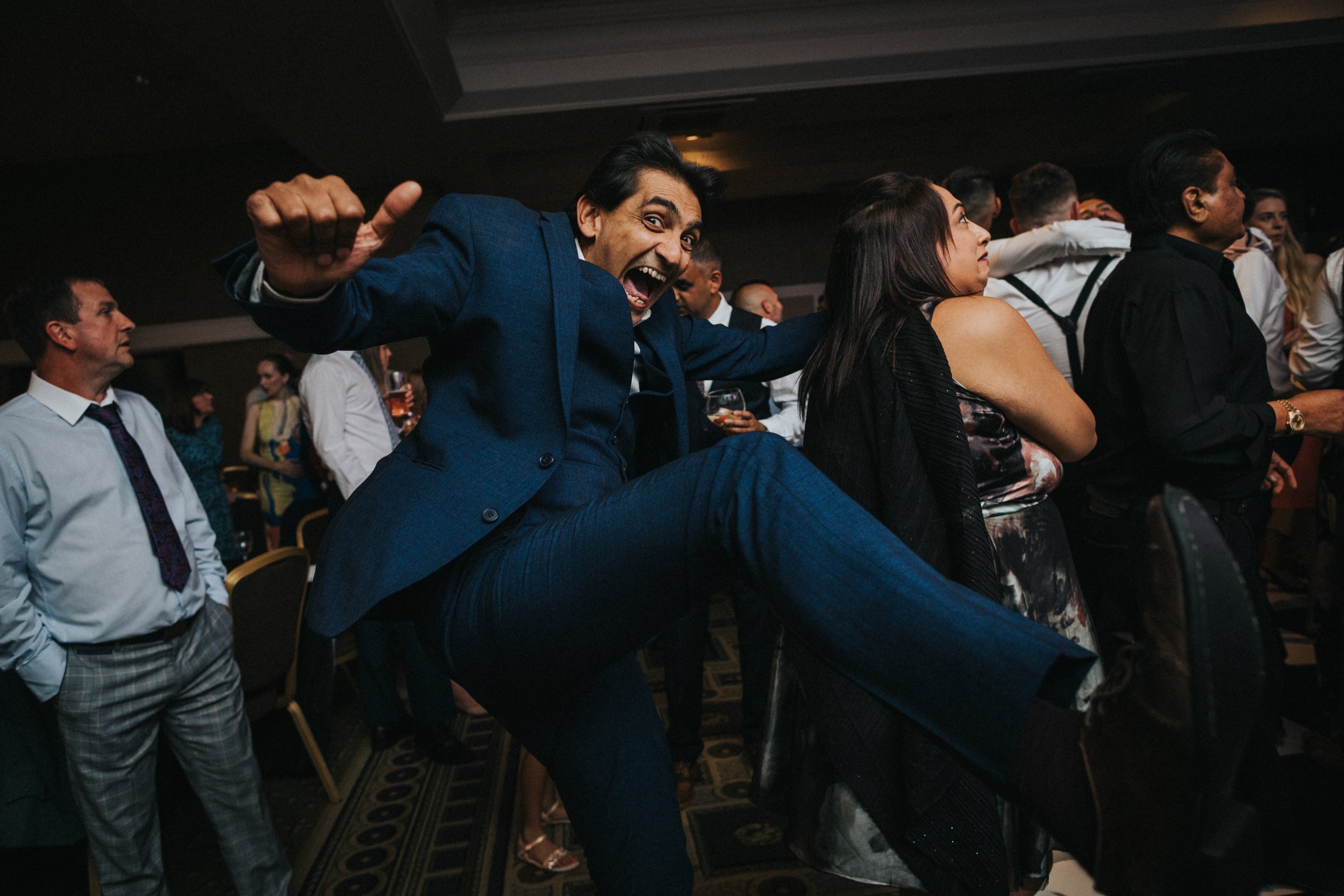 Male wedding guest in blue suit does a karate kick.