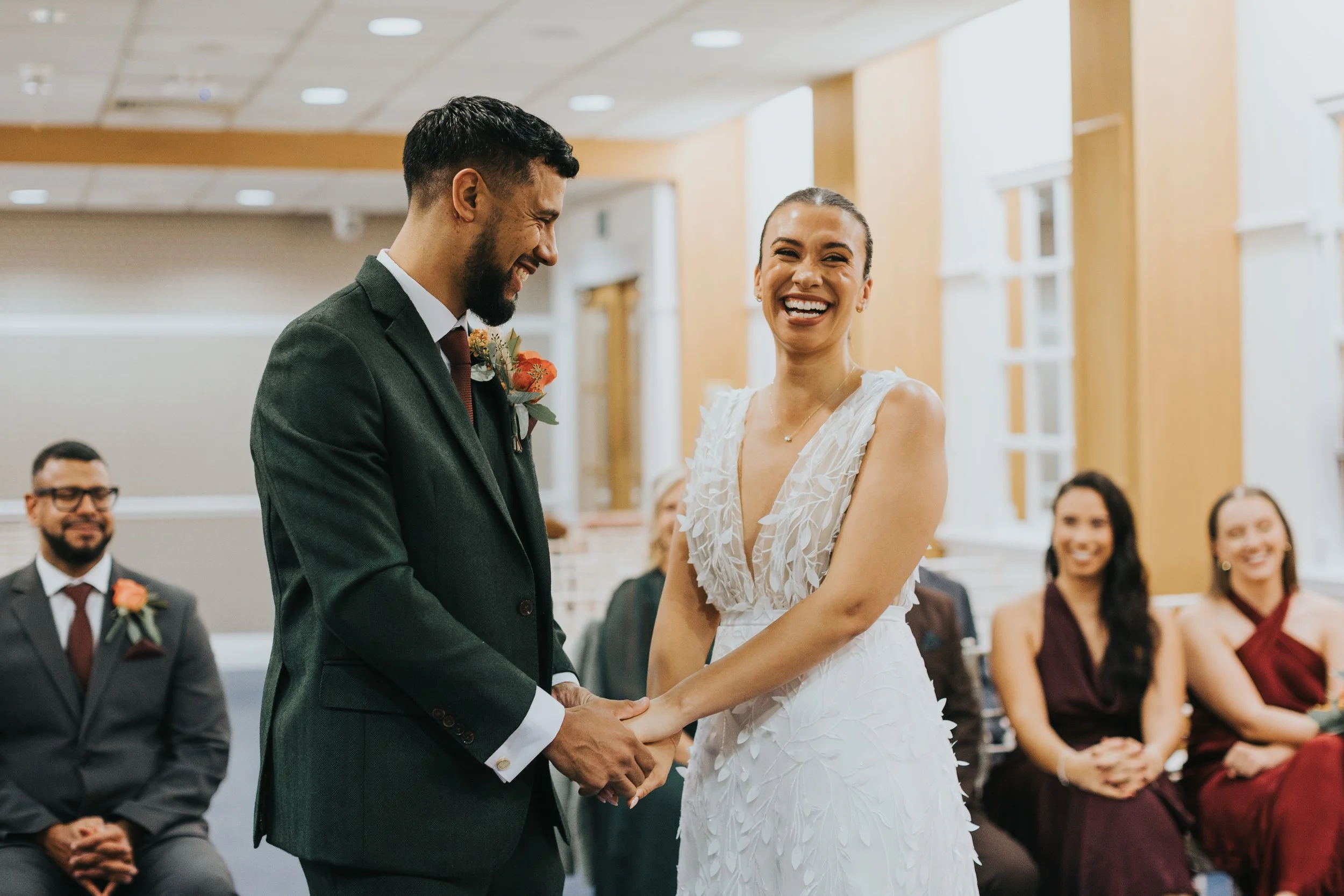 Bride and groom smile joyously as they say their vows in Manchester registry office. 