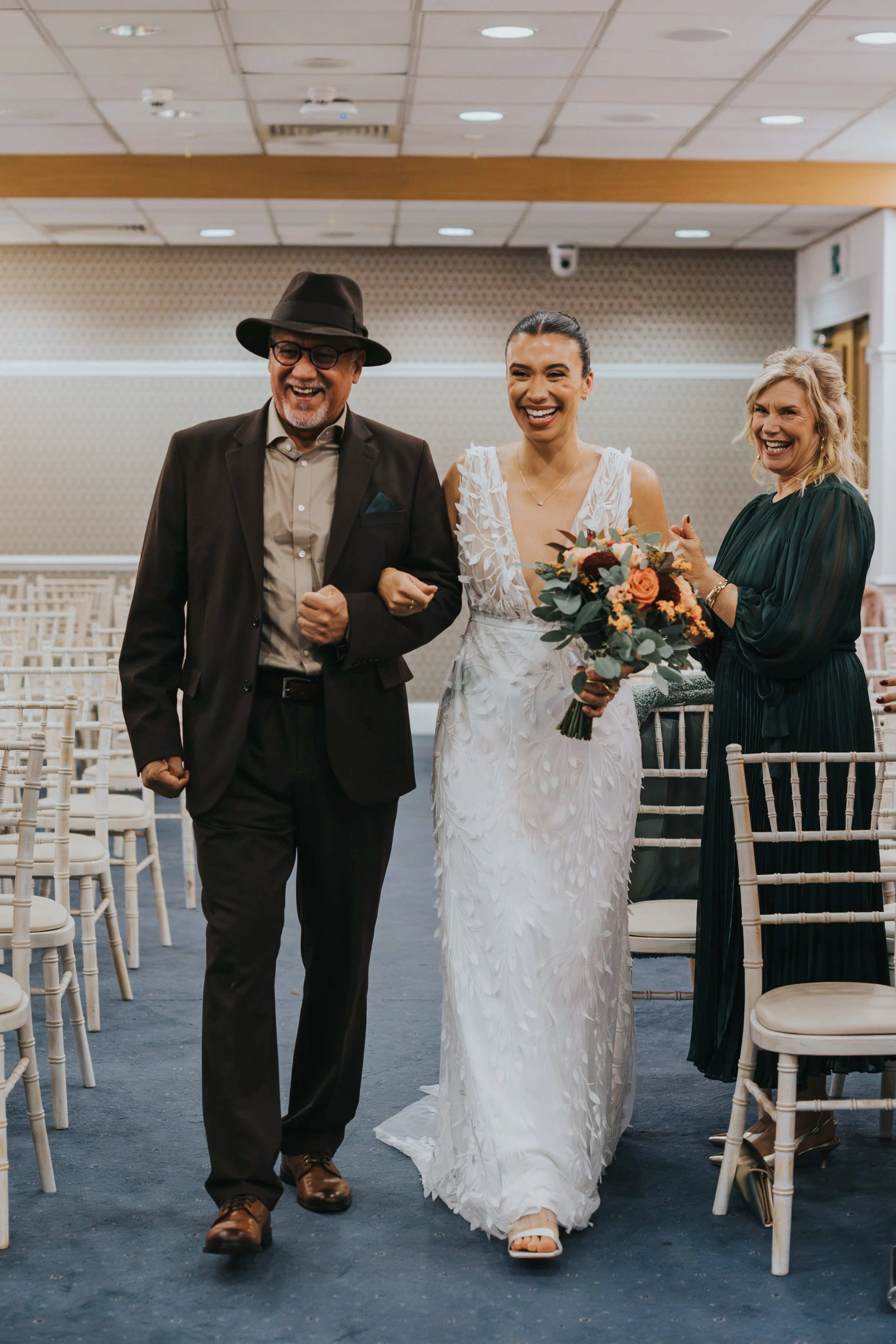 Father of the bride and bride both laugh while walking down the aisle at The Pankhurst Suite Manchester