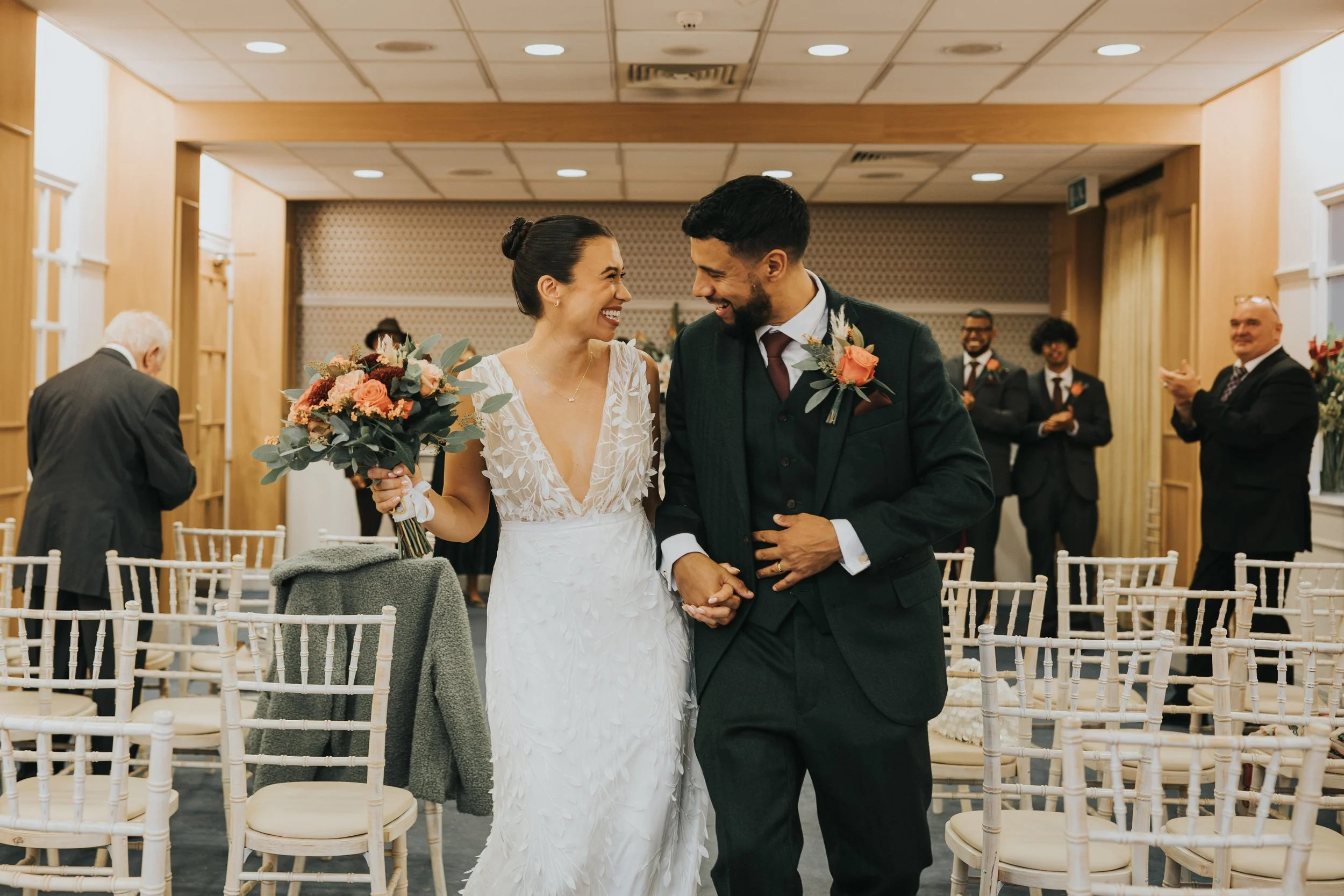 Bride and Groom walk back down the aisle together after being married in their Manchester registry office small wedding laughing and smiling 