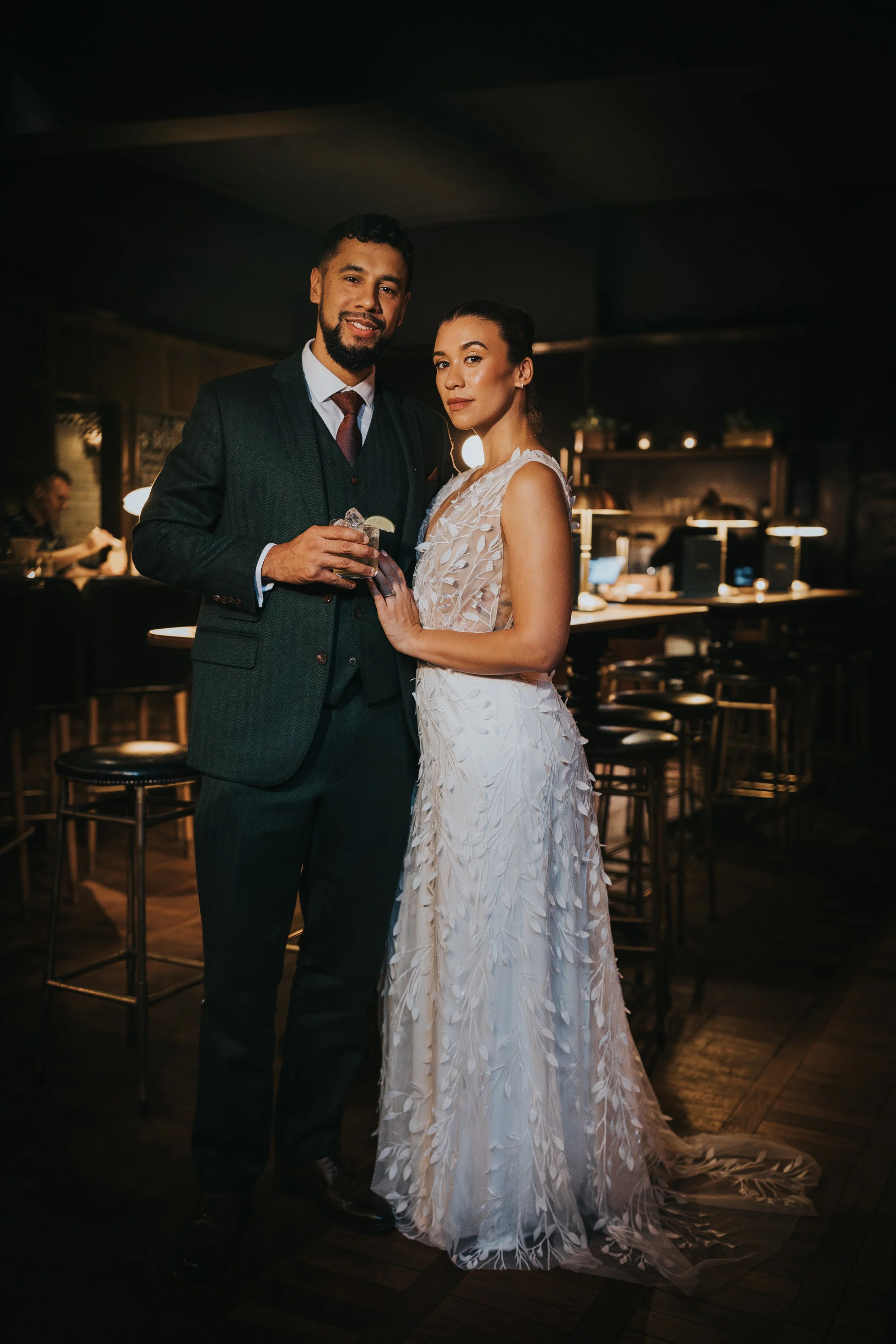 Bride and Groom stand serious faced in the Hawksmoor Bar, Manchester
