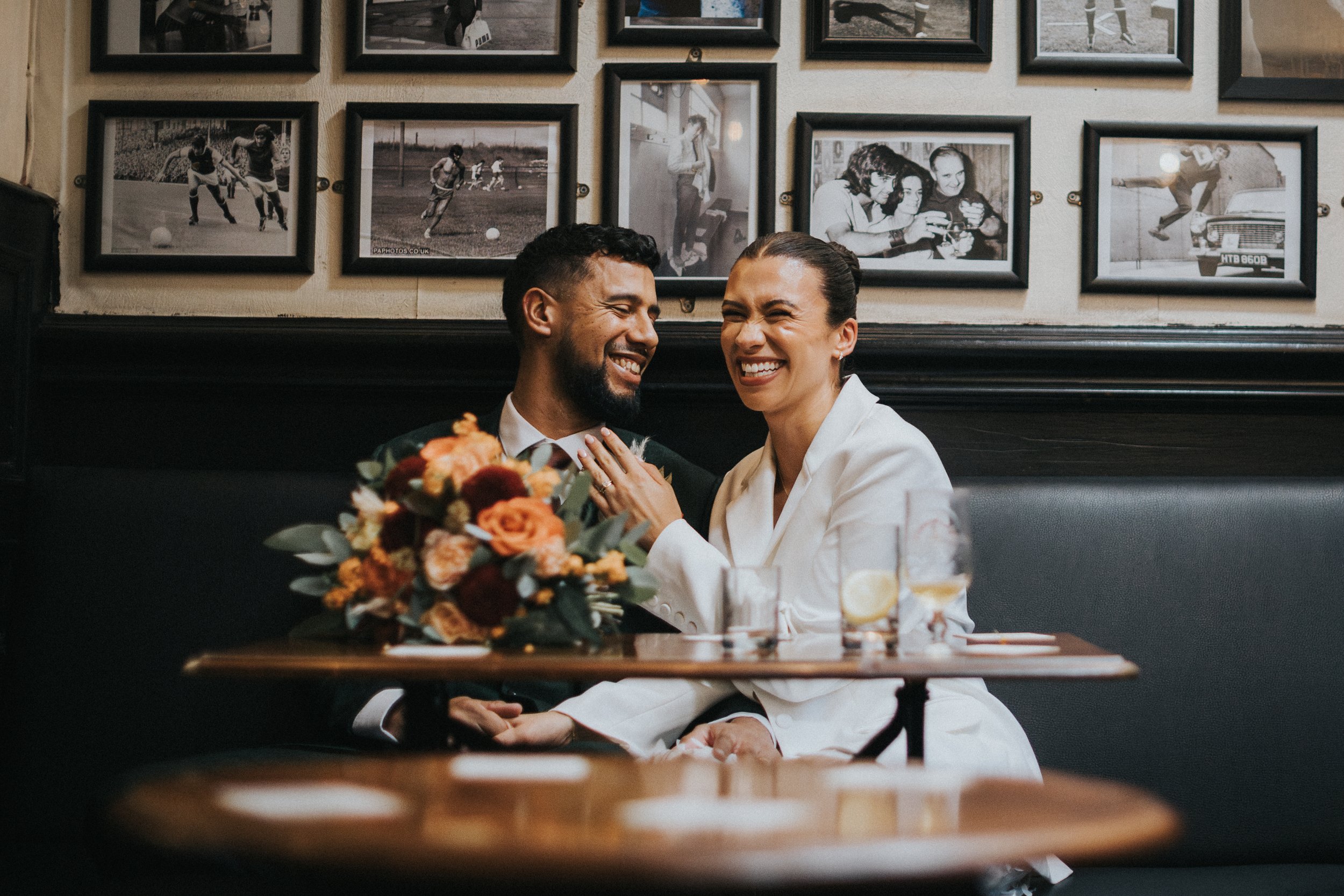 Bride and Groom sit laughing in pub together as they shelter from the storm outside. 
