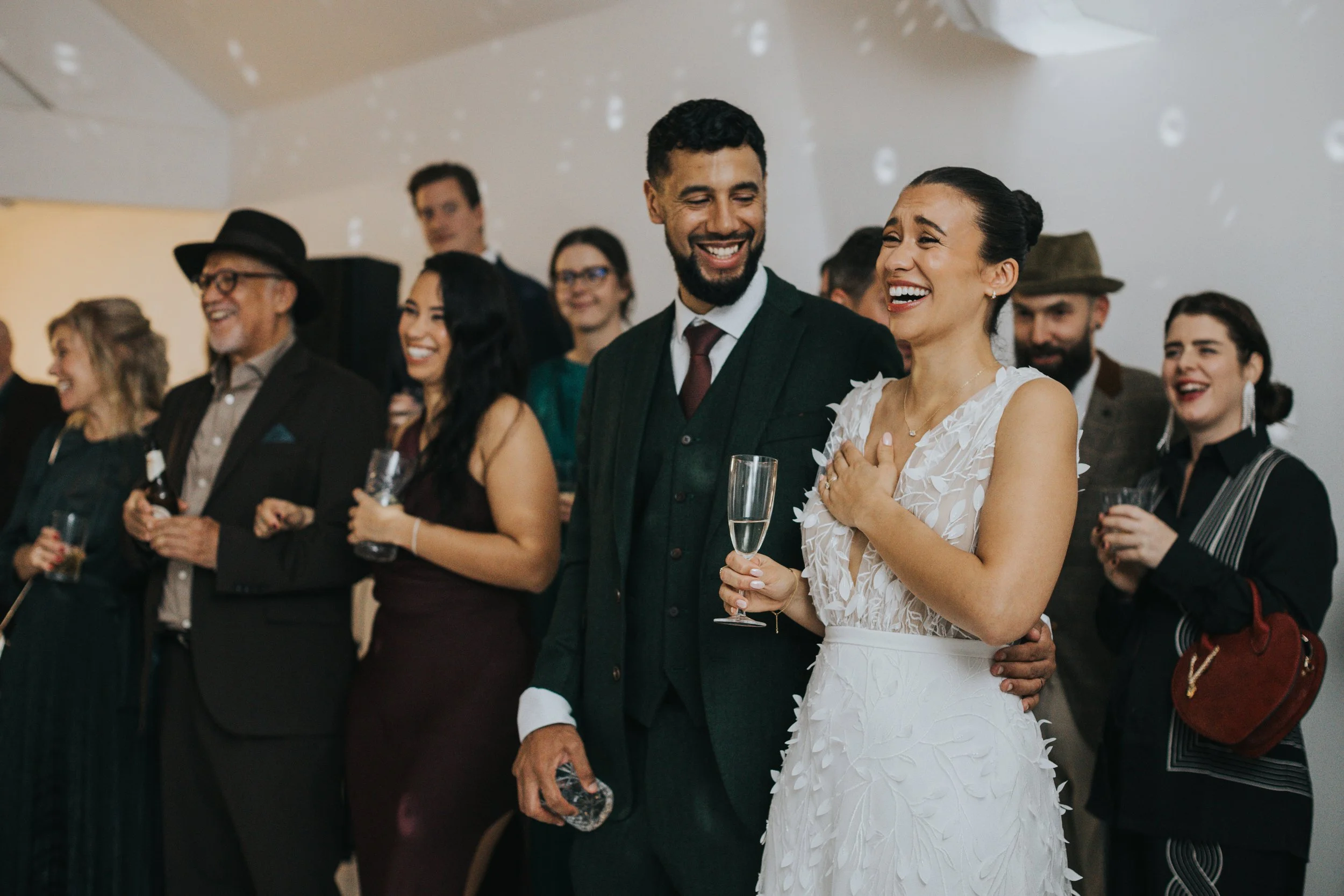 Bride and groom laughing at speeches on dance floor. 