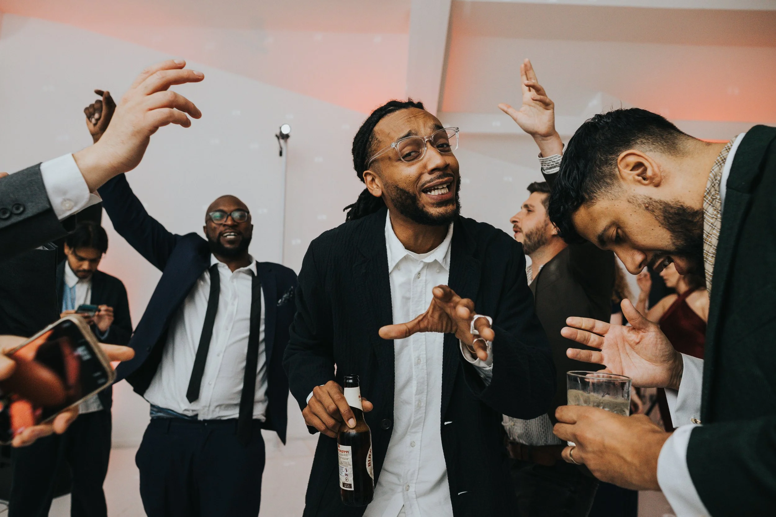 Wedding guest with dreadlocks and glasses singing and dancing