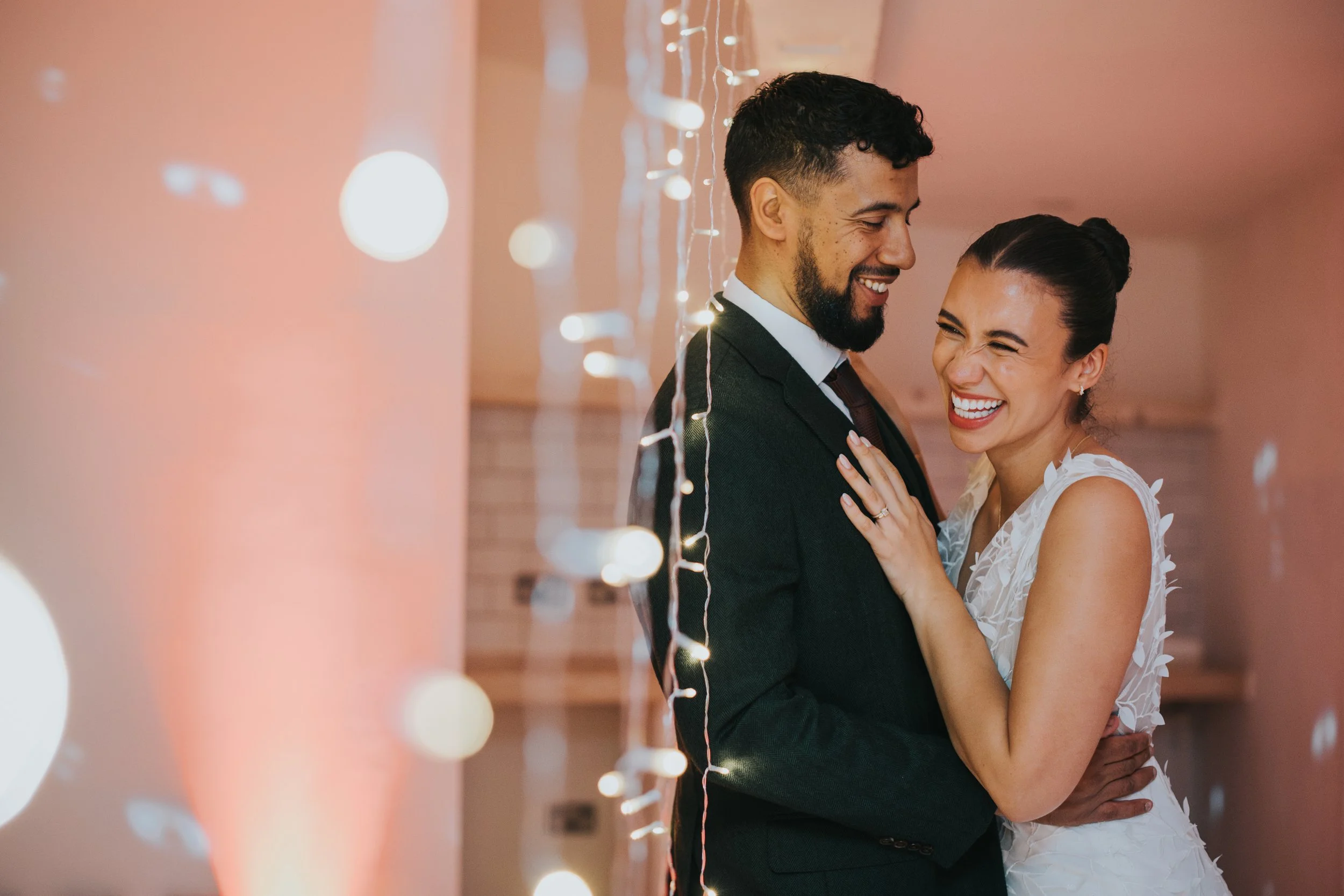 Bride and groom laughing amongst fairy lights at Fivefour Studios.