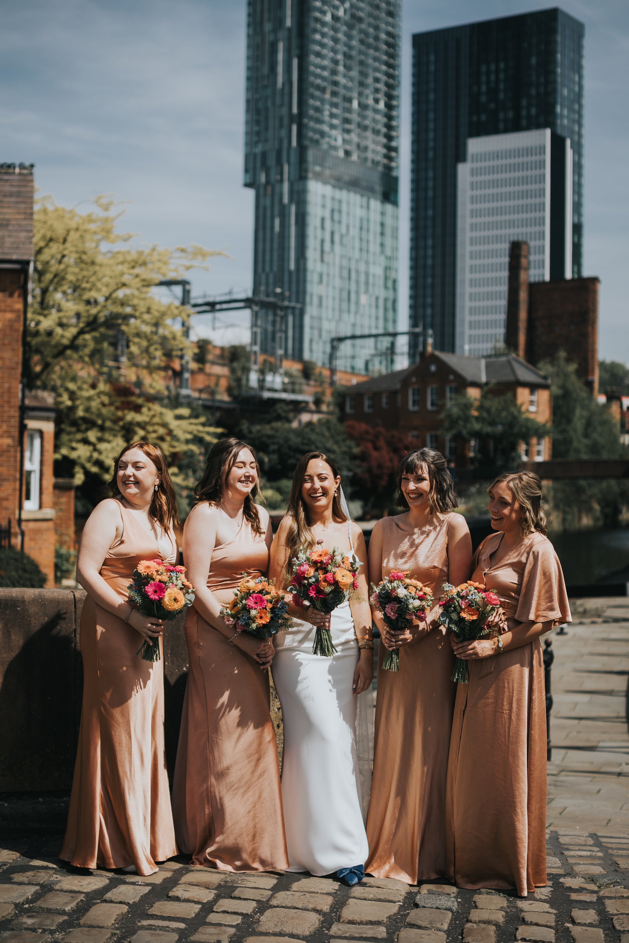 Bride and Bridesmaids have a photo by canal. 