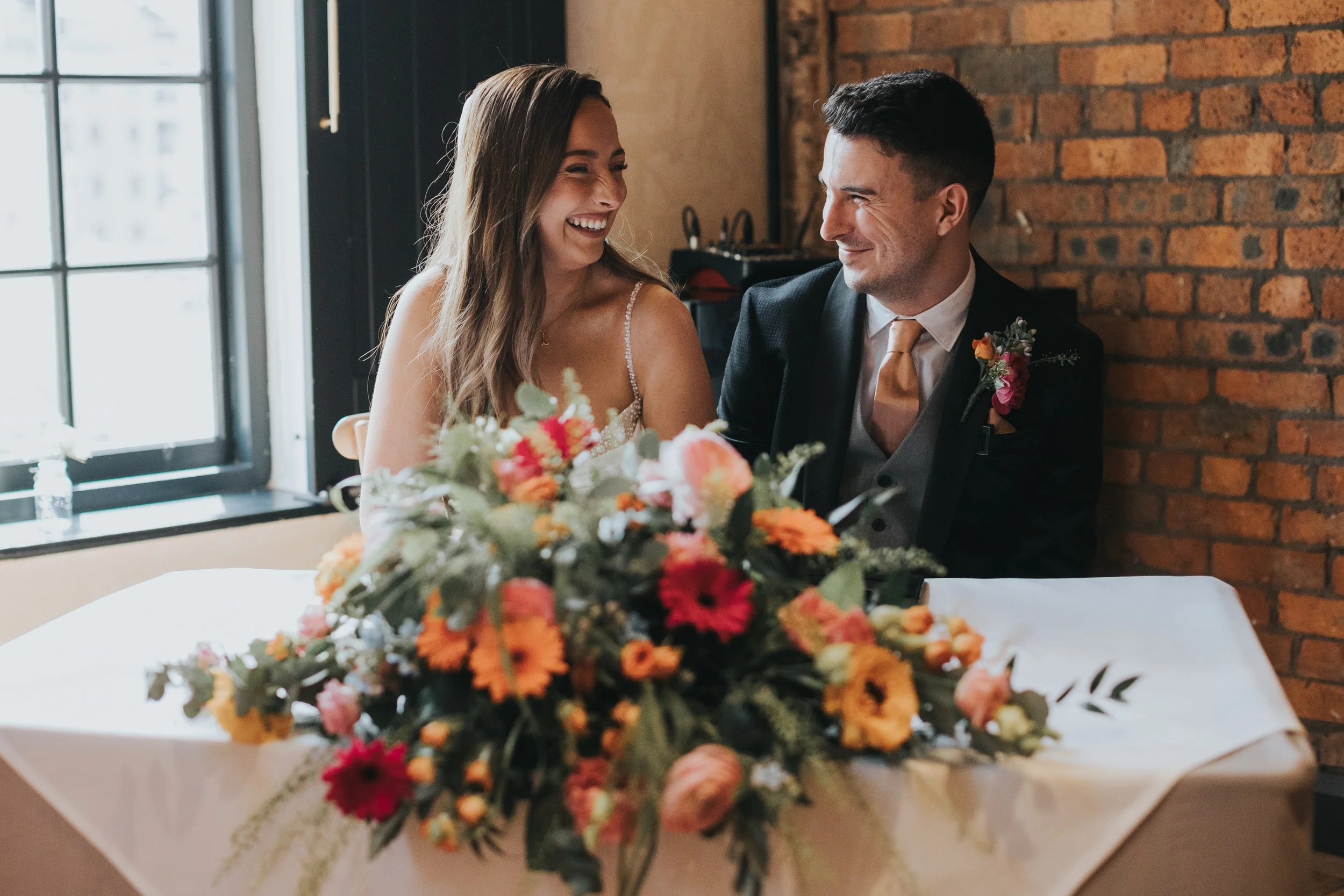 Bride and Groom laughing as they sign the register. 