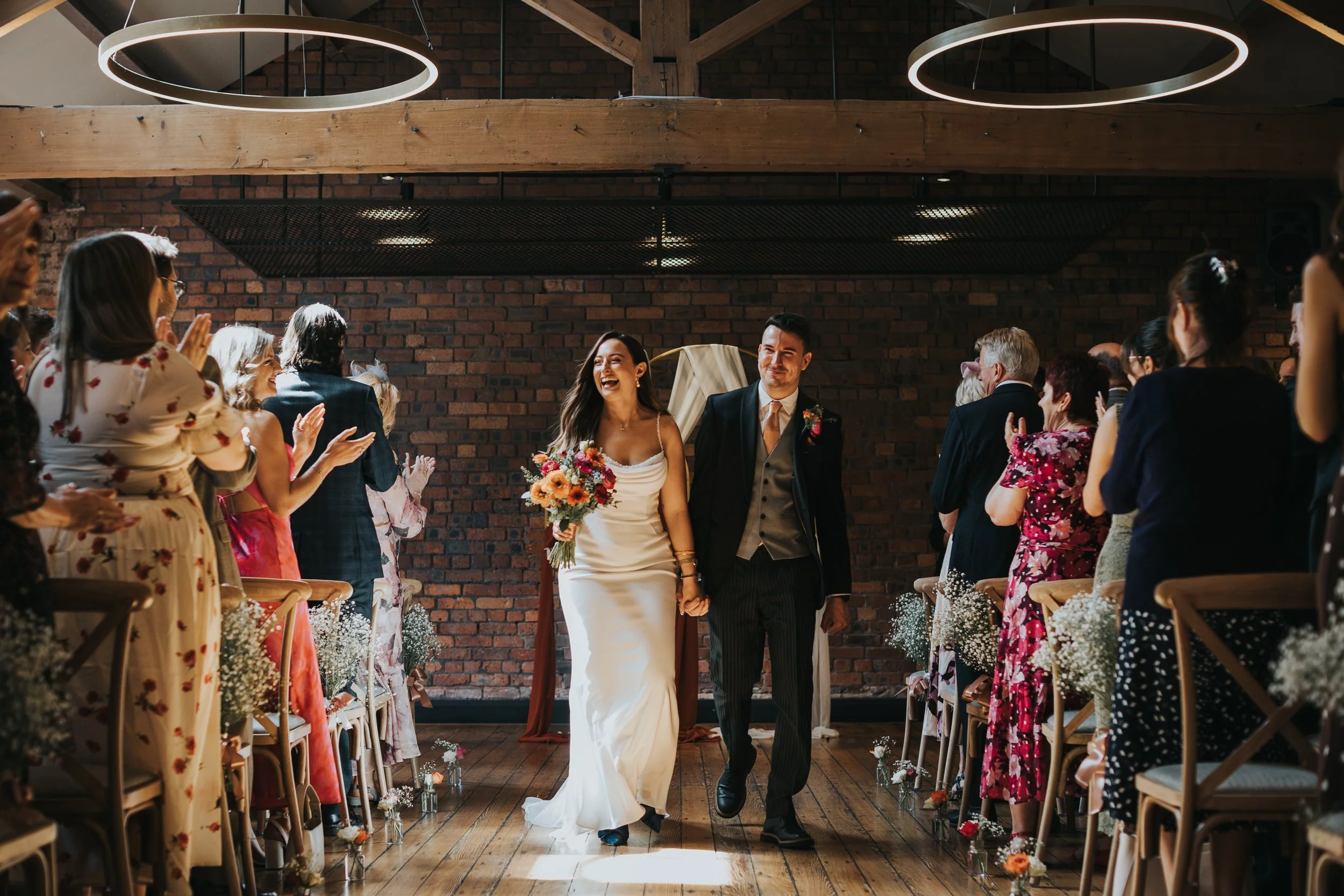 Bride and Groom walk back down the aisle together after their wedding ceremony at the Castlefield Rooms, Manchester. 