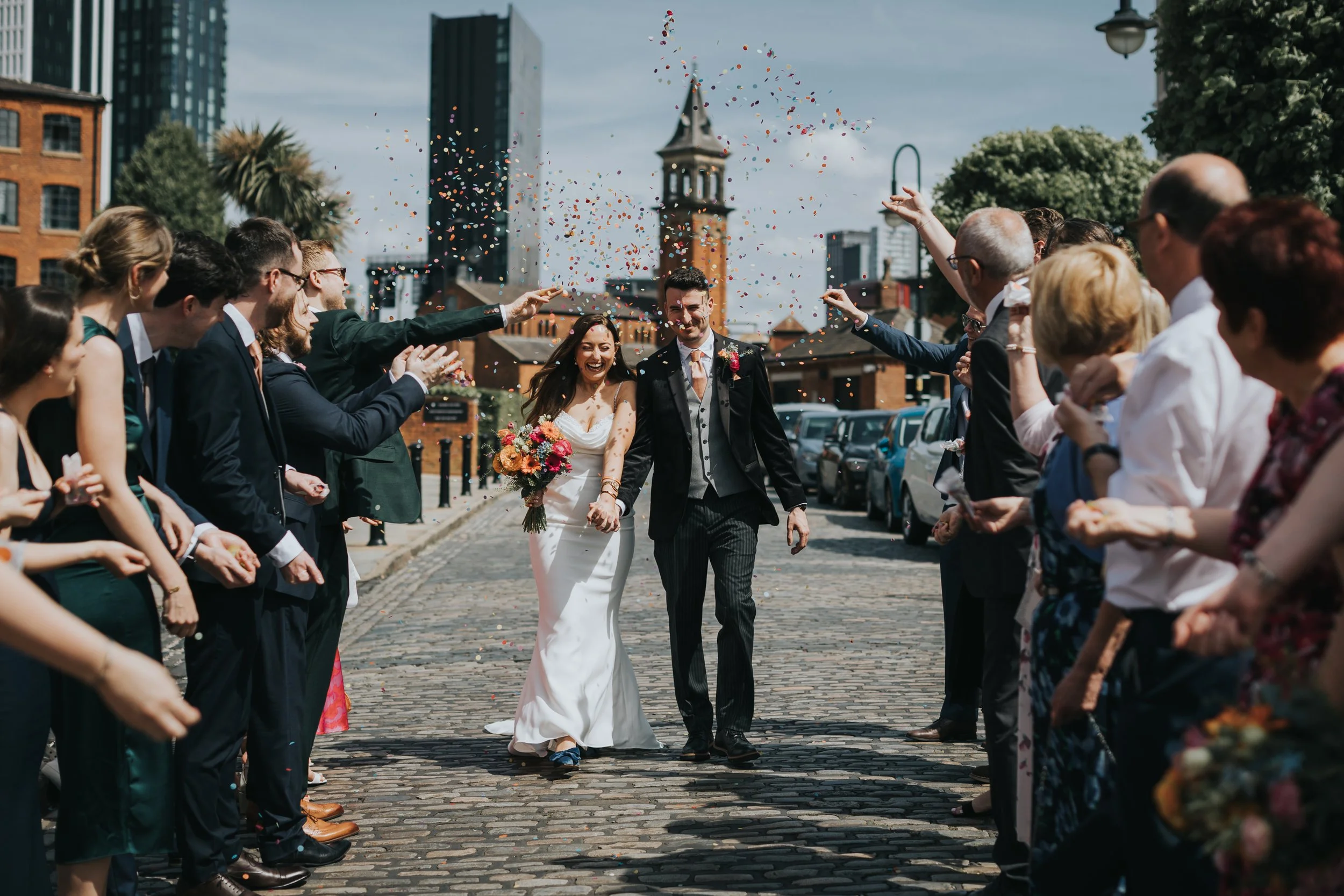 Bride and Groom have confetti thrown at them on cobbled street in Manchester. 