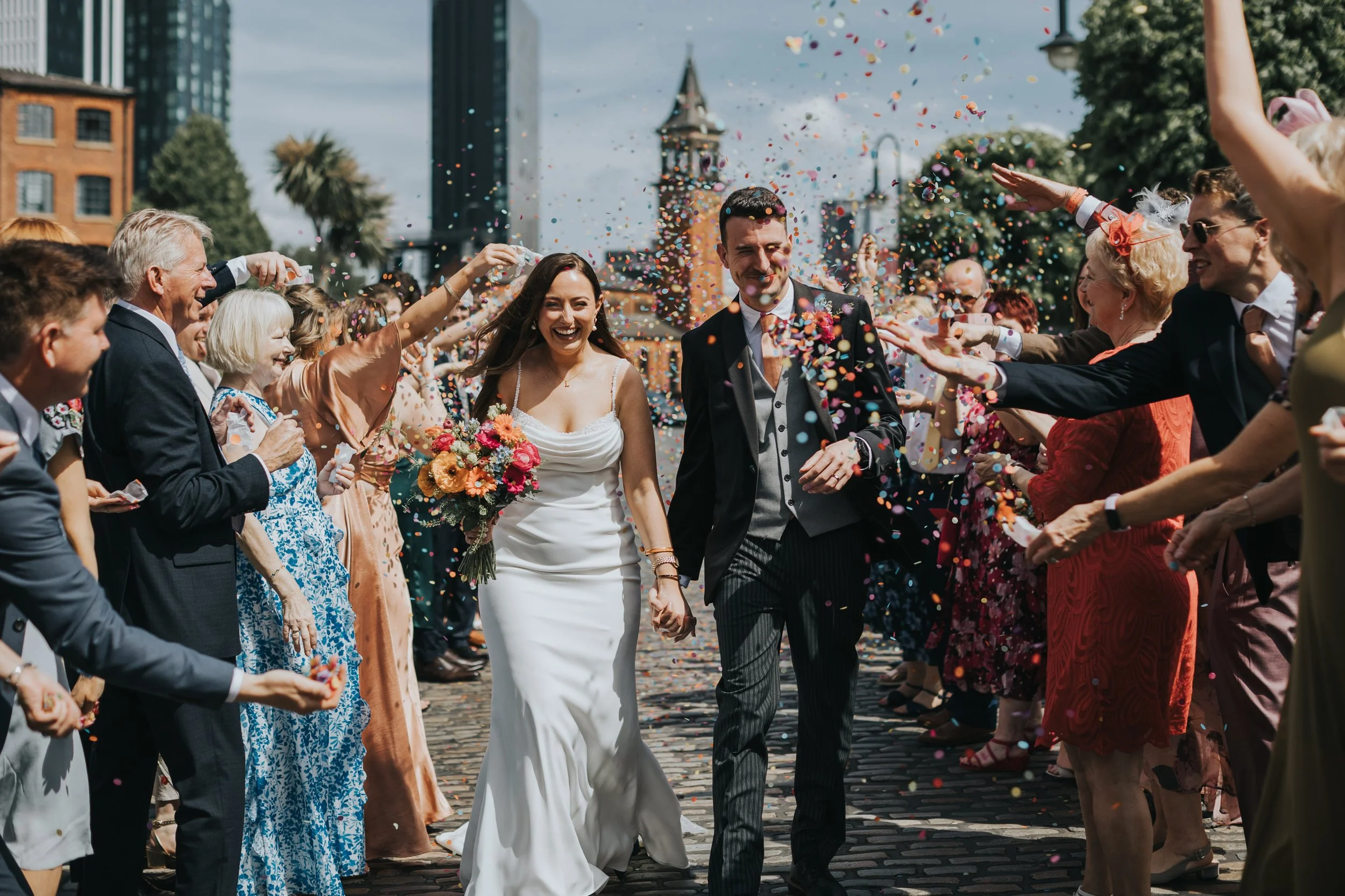 Bride and Groom laughing as their guests throw confetti. 
