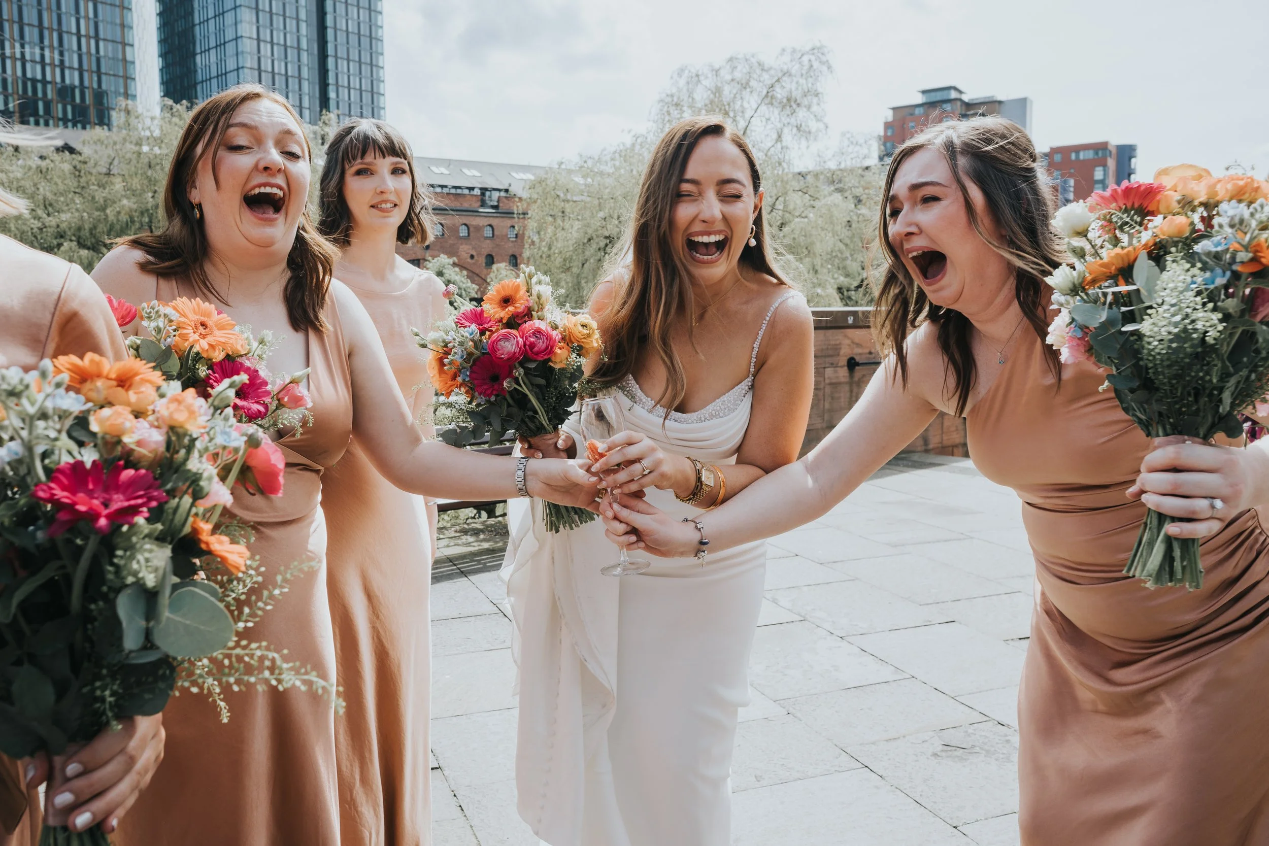 Bride and Bridesmaids laugh after one of them spills a drink. 