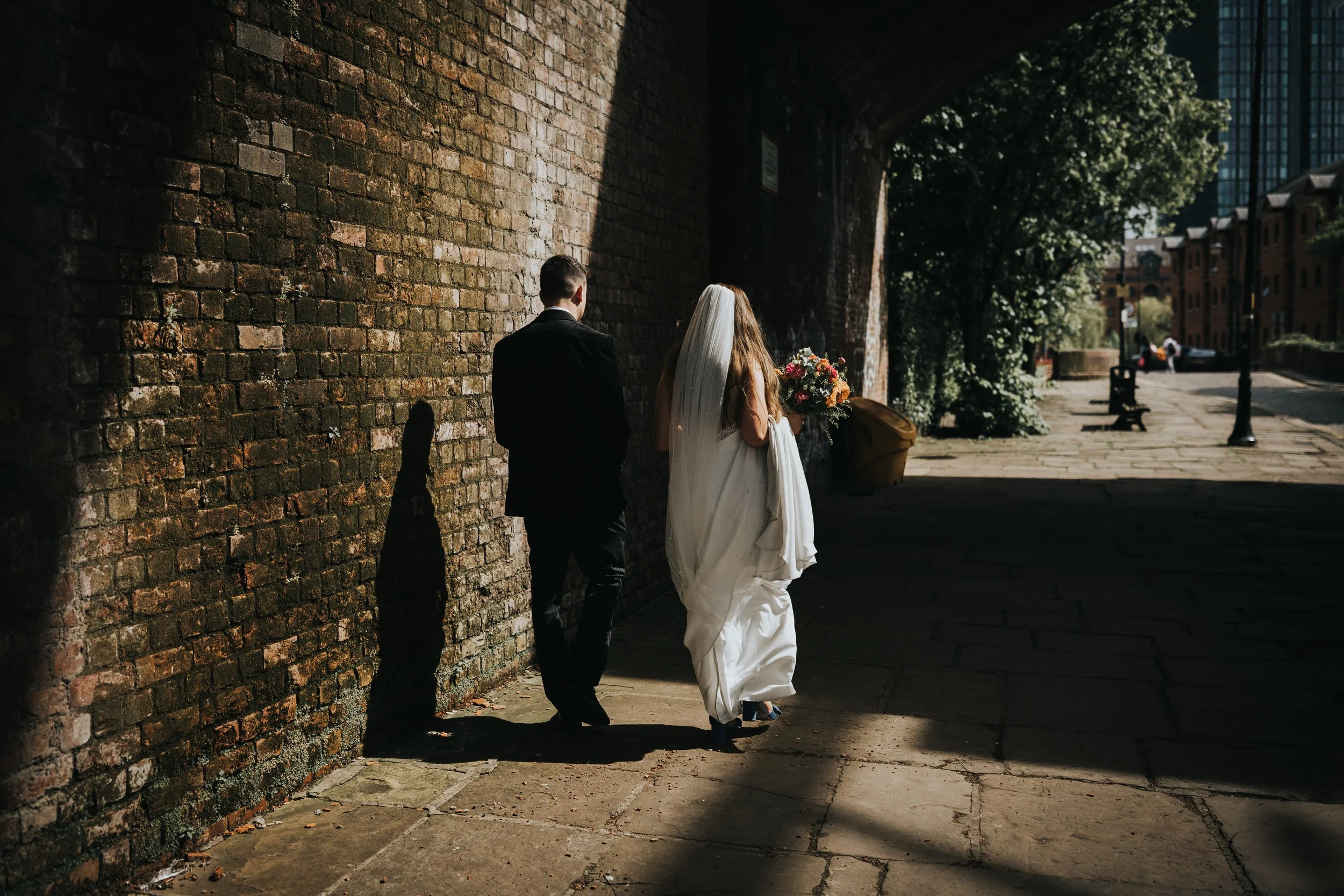 Bride and groom walk away together in the sunlight. 