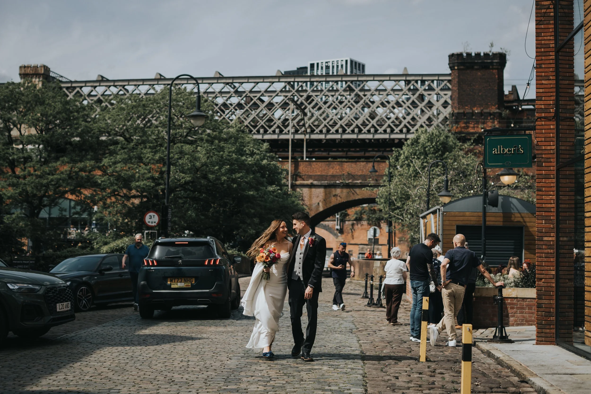 Bride and Groom walk down busy street in Manchester. 