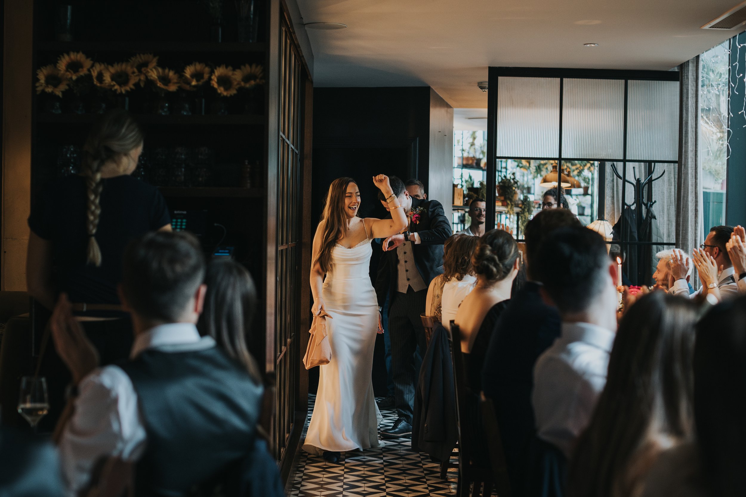 Bride and groom entering the dining room to cheering guests. 