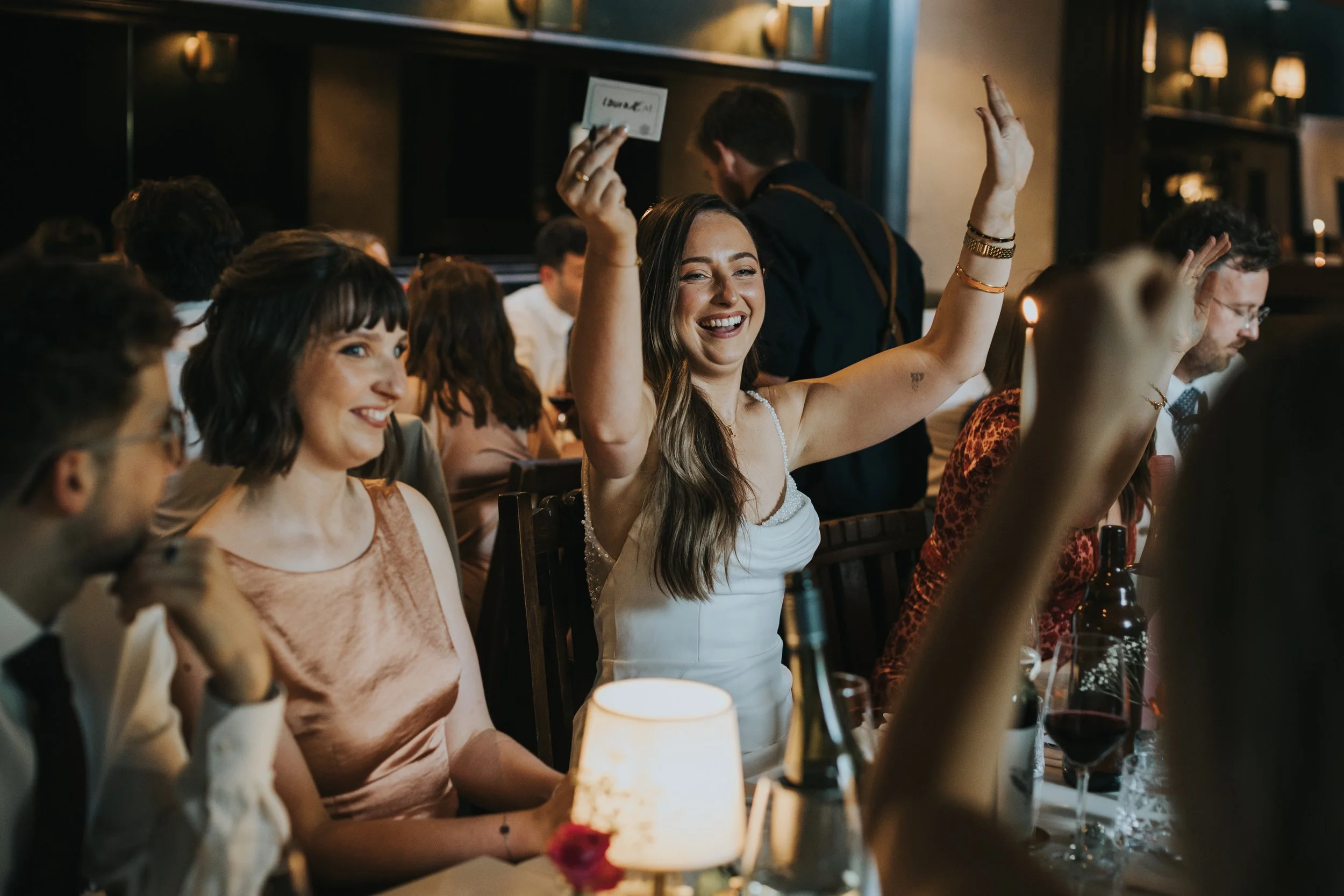 Bride holding up table place card laughing. 