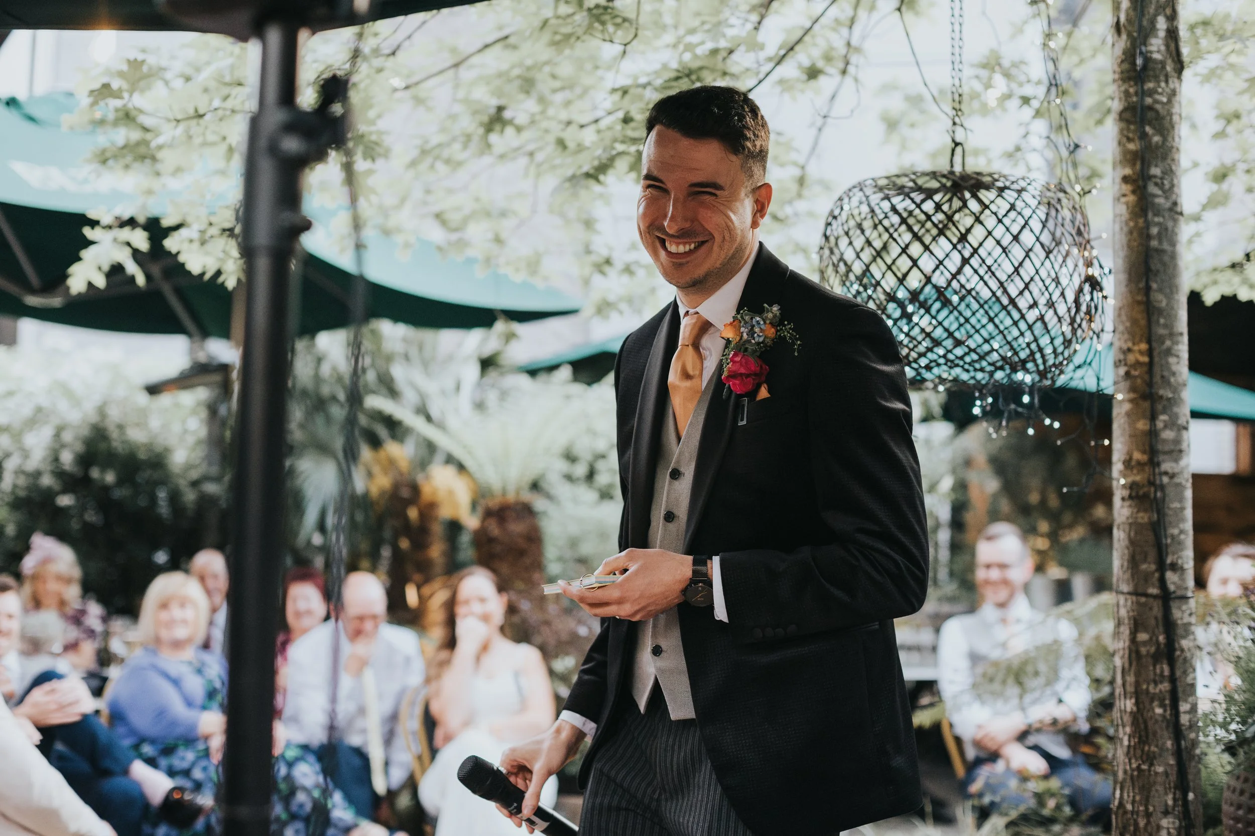 Groom smiling as he gives his speech. 