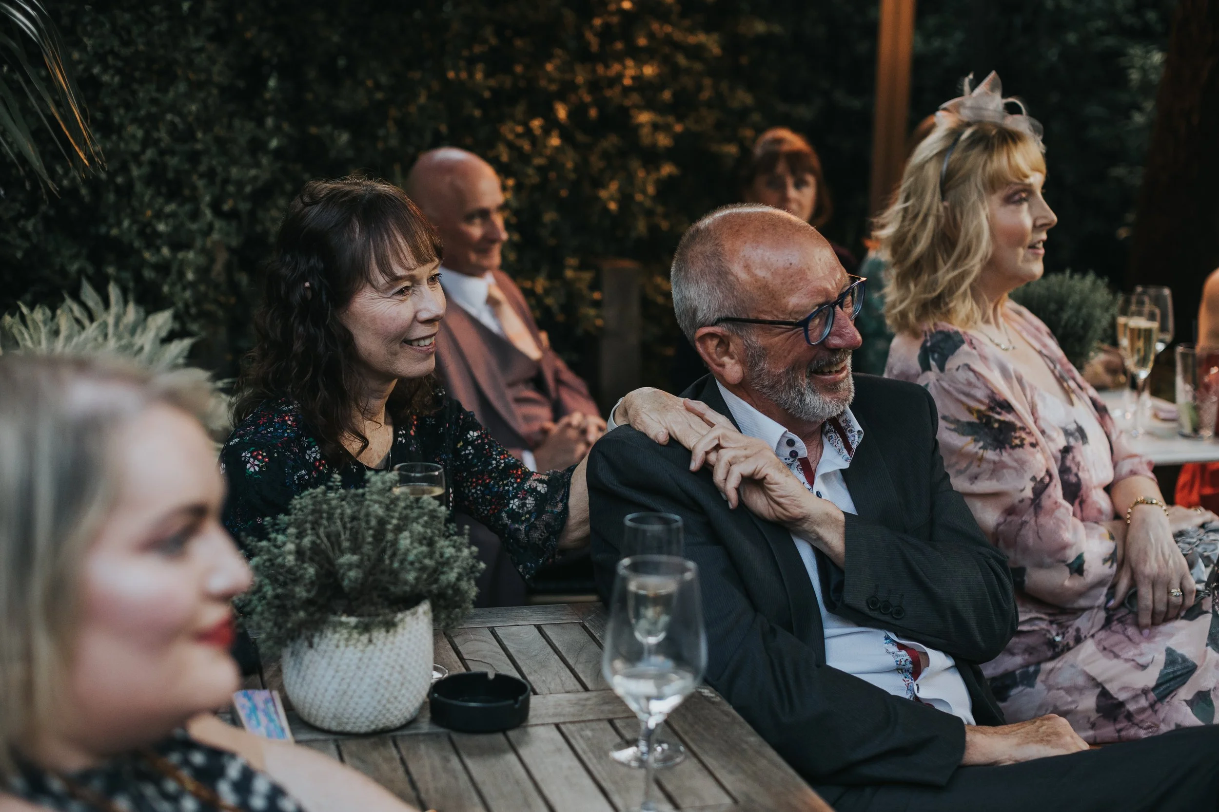 Wedding guests hold hands as they listen to speeches. 