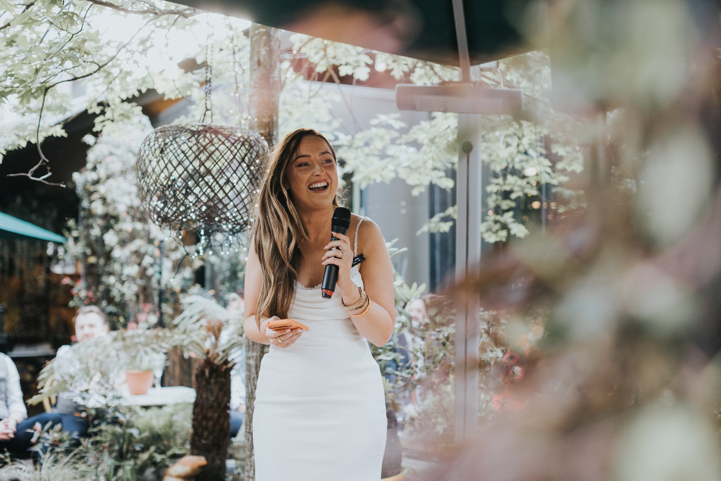 Bride laughing as she gives her speech in Black Friars jungle garden. 