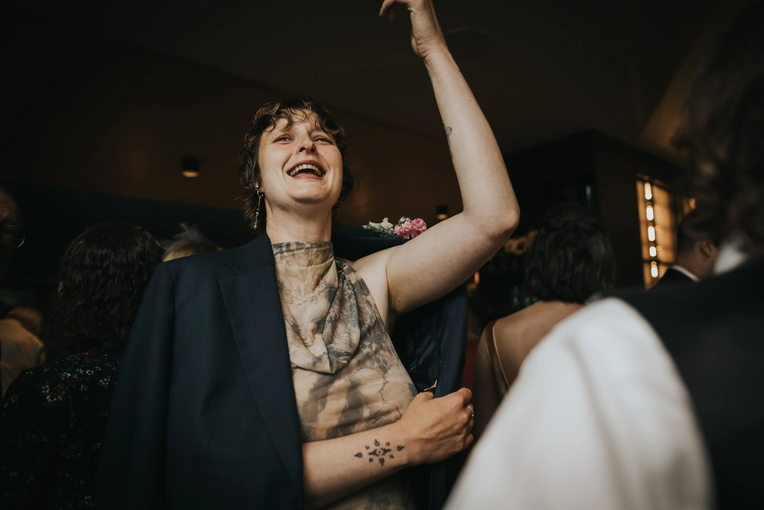 Wedding guest has her arms in the air ready to party. 