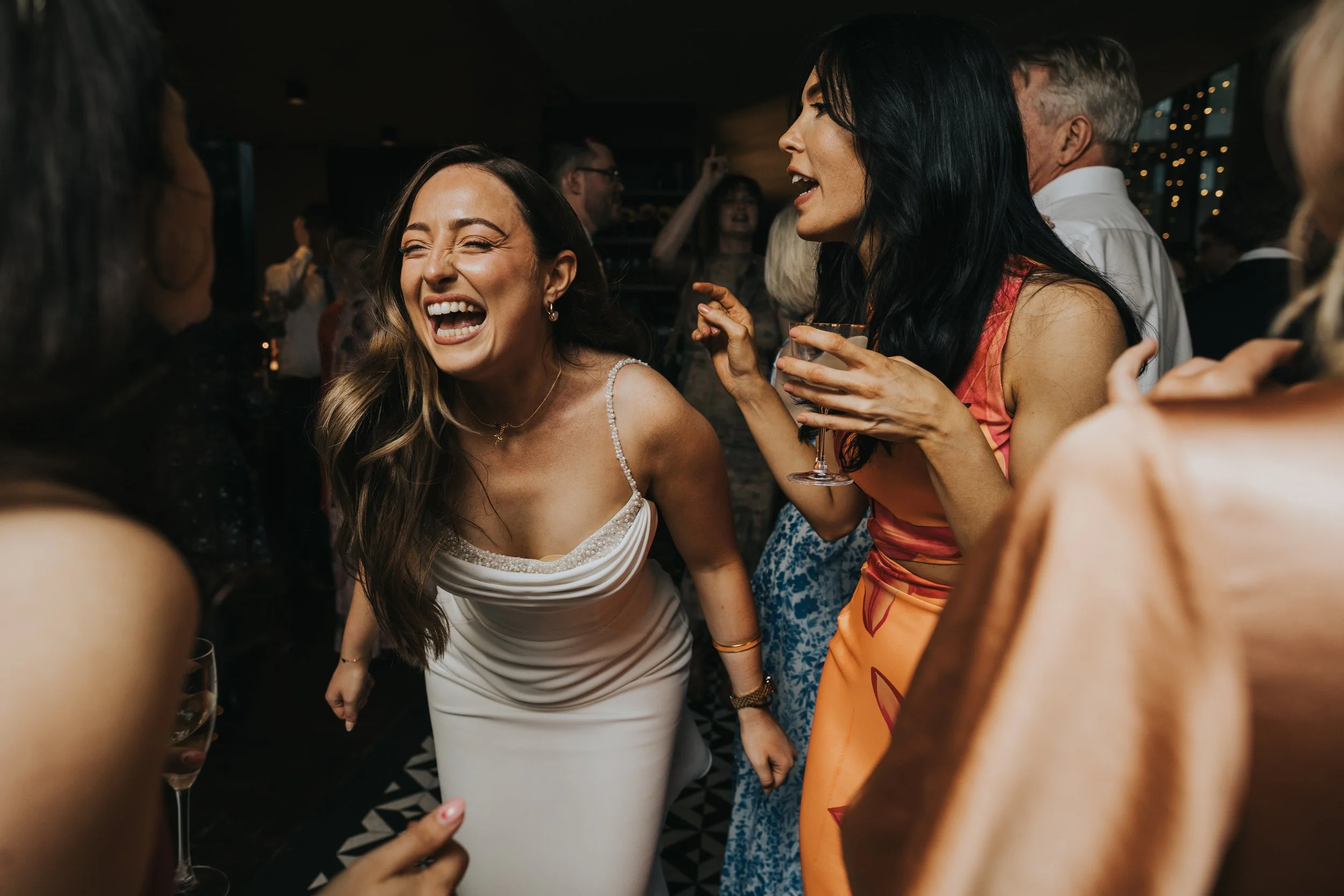 Bride leans forward laughing as she dances. 