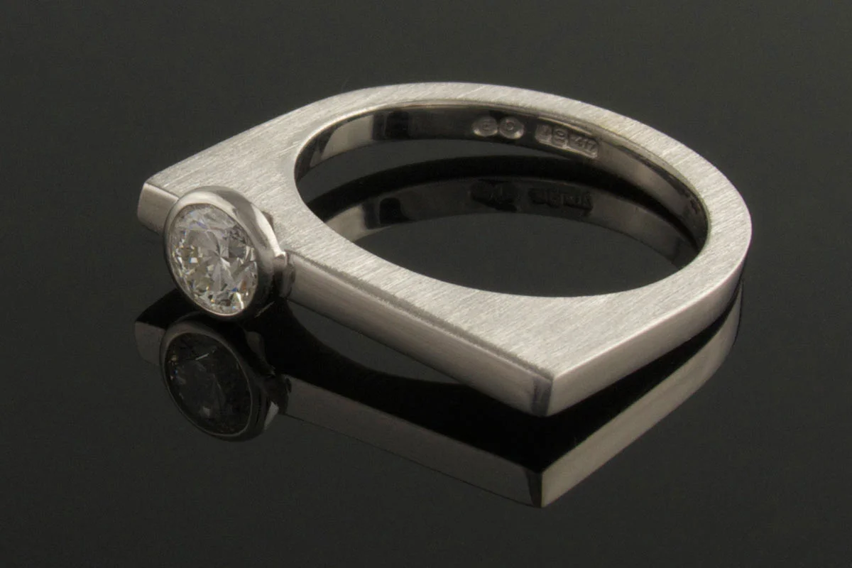 White gold U-shaped ring with bezel set diamond
