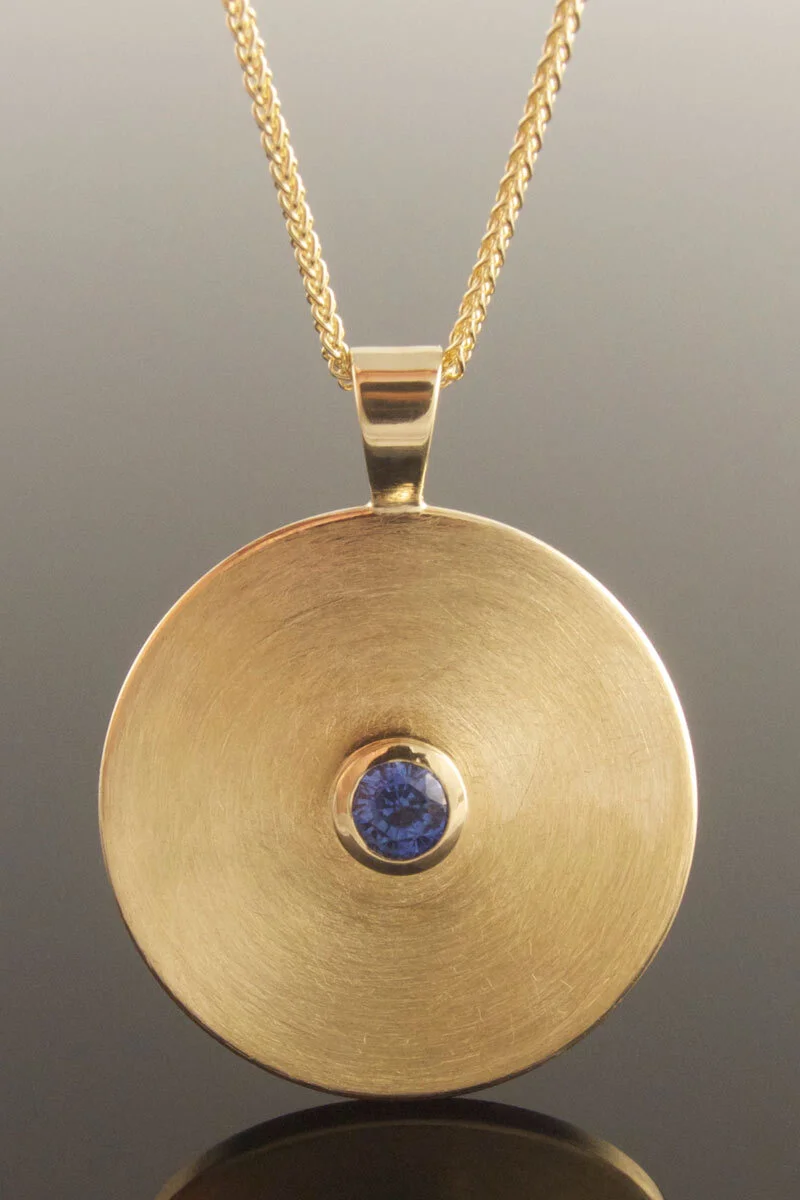 Yellow gold disc pendant with sapphire