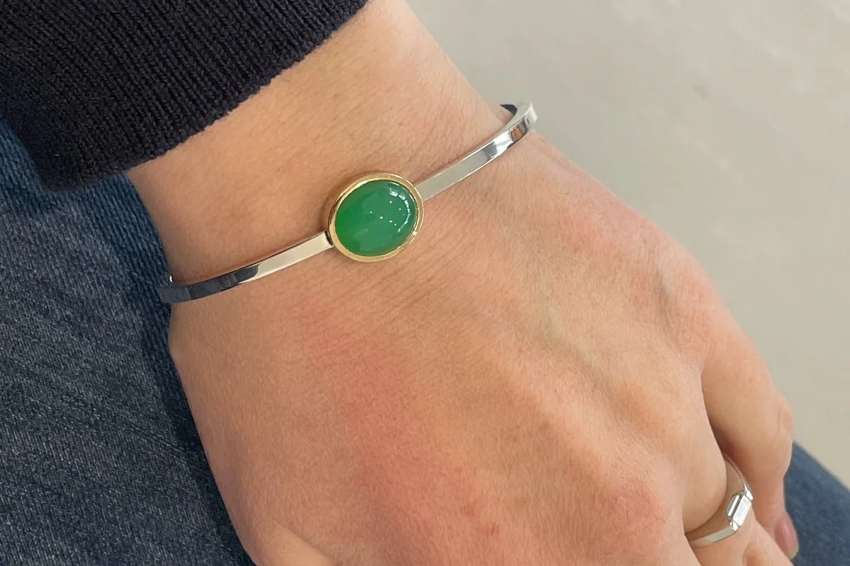 Asymmetrical bezel set chrysoprase bangle in silver and 9ct yellow gold on wrist