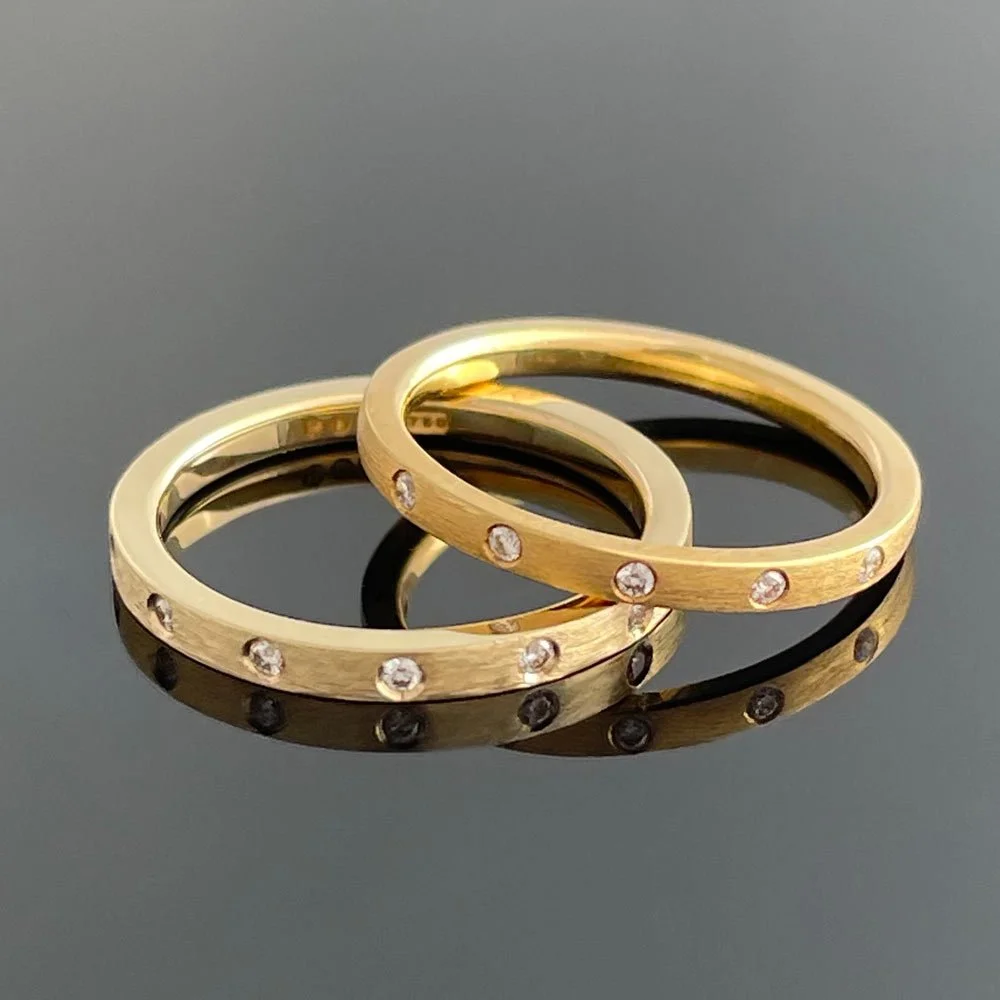 Softly curved 18ct yellow gold band with flush set diamonds resting on a flat profile 9ct yellow gold ring with punch set diamonds