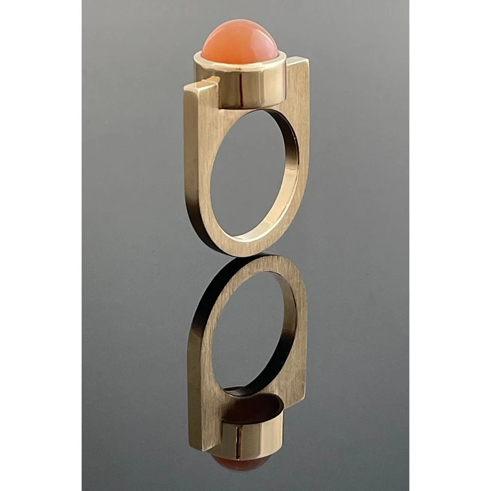 Cabochon orange moonstone bezel set in yellow gold on a flat topped contemporary gold ring