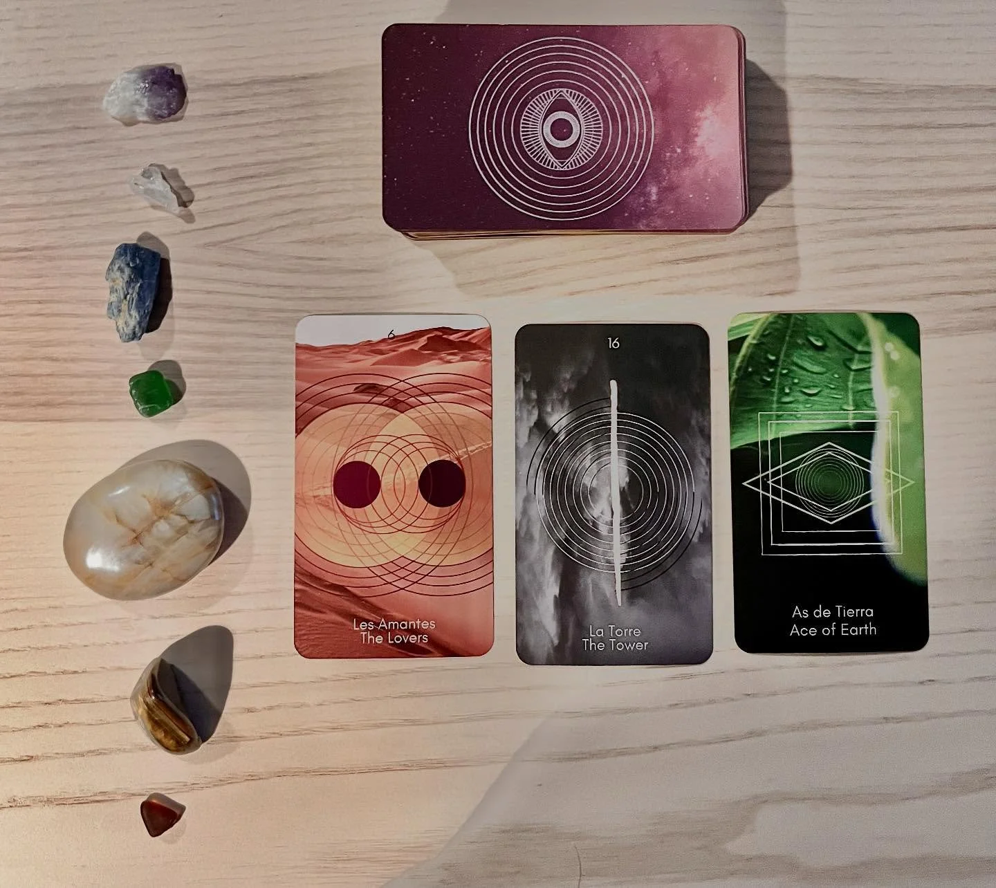 I love this deck so much! 

Image ID: 7 stones lie to the left of a three card pull.  The past card lovers, the present the tower, and the future card is:

ACE OF EARTH / AS DE TIERRA / ACE OF PENTACLES
Beginning.
Fruitful things are beginning. The A
