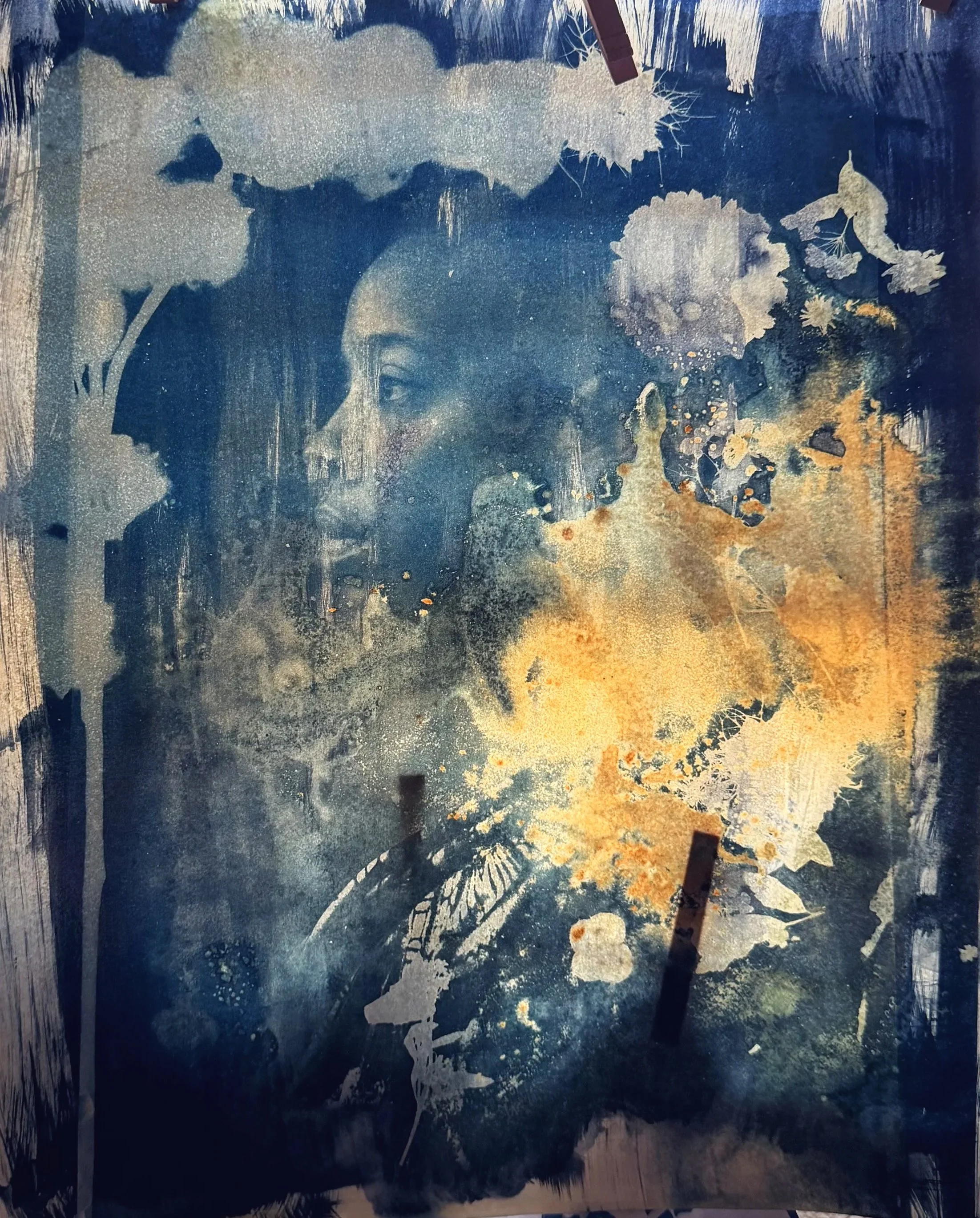 A mixed media artwork featuring a depiction of a woman's face in profile, surrounded by abstract and floral elements. The color palette includes shades of blue, beige, and white, with textured brushstrokes and layered splashes of paint creating a dre