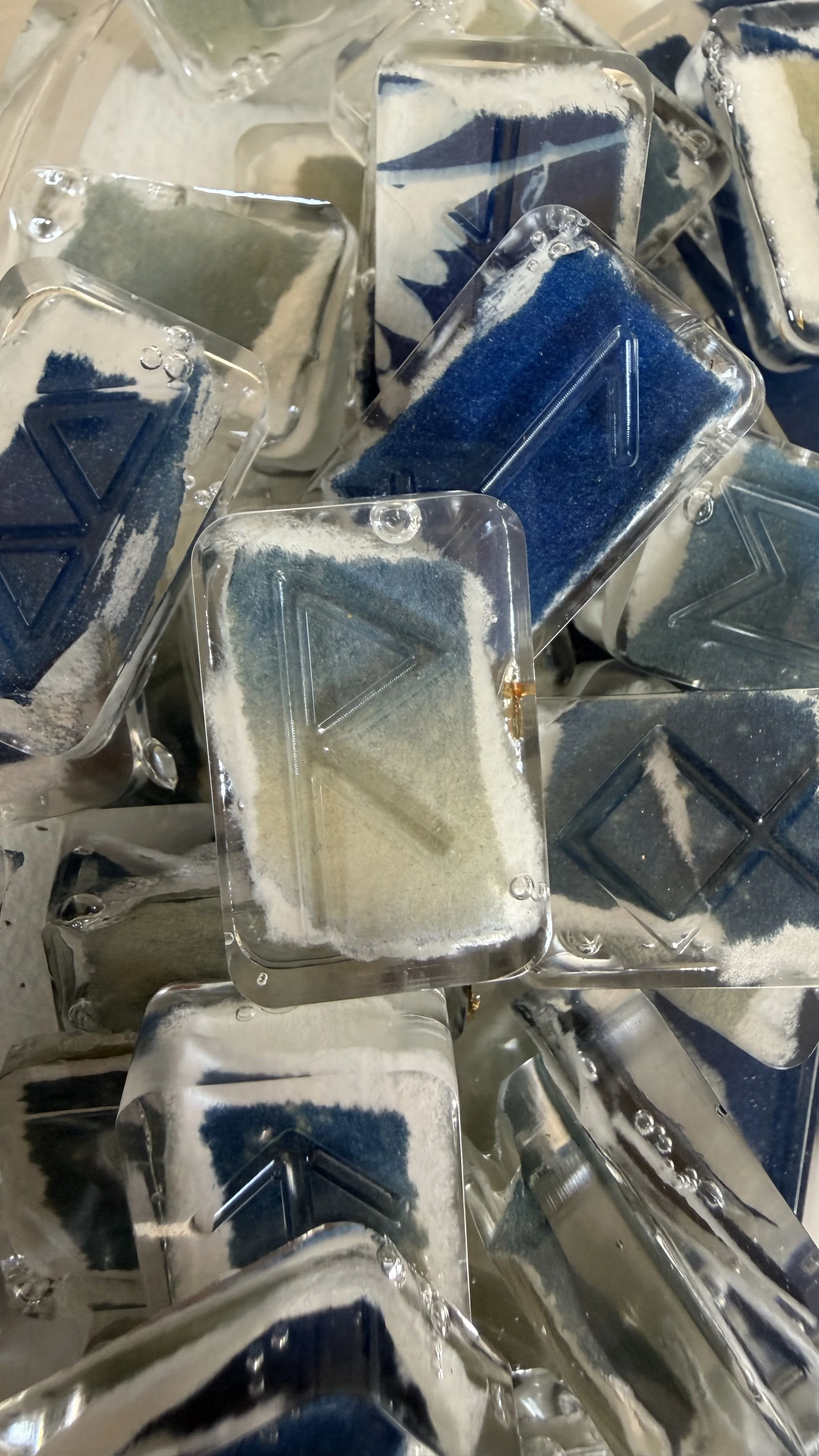 Close-up of ice cubes with some containing colorful food dye residue inside.