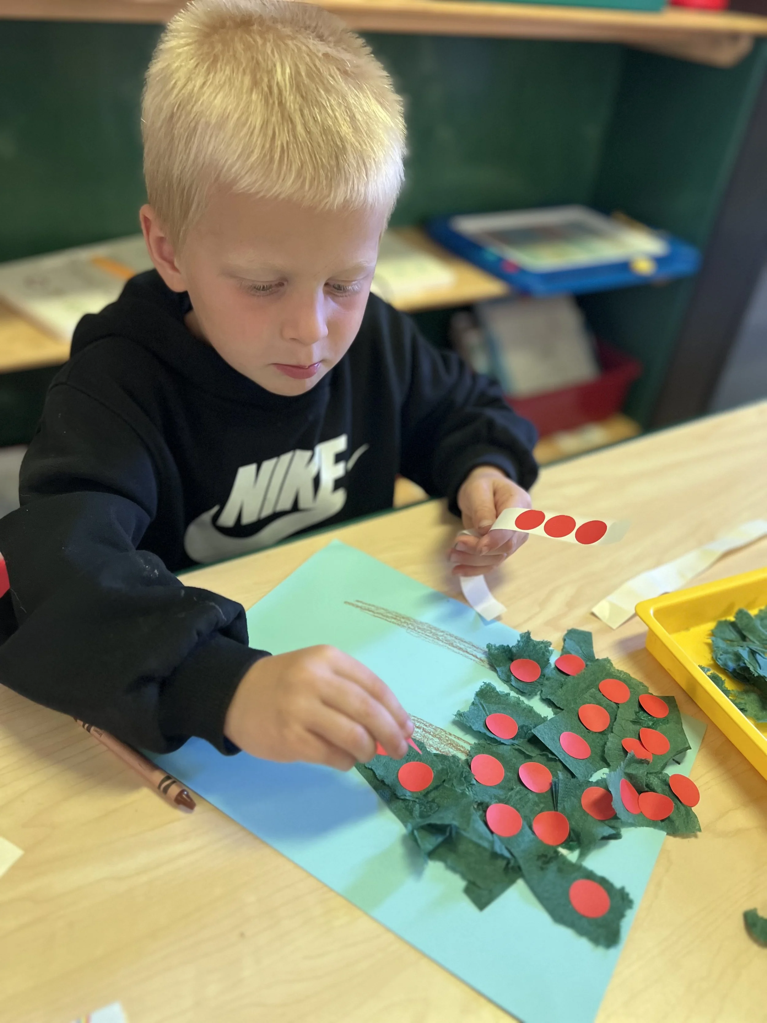 preschool student at Leap Ahead Preschool in Boise, Idaho, developing fine motor skills through a hands on apple tree play based art activity