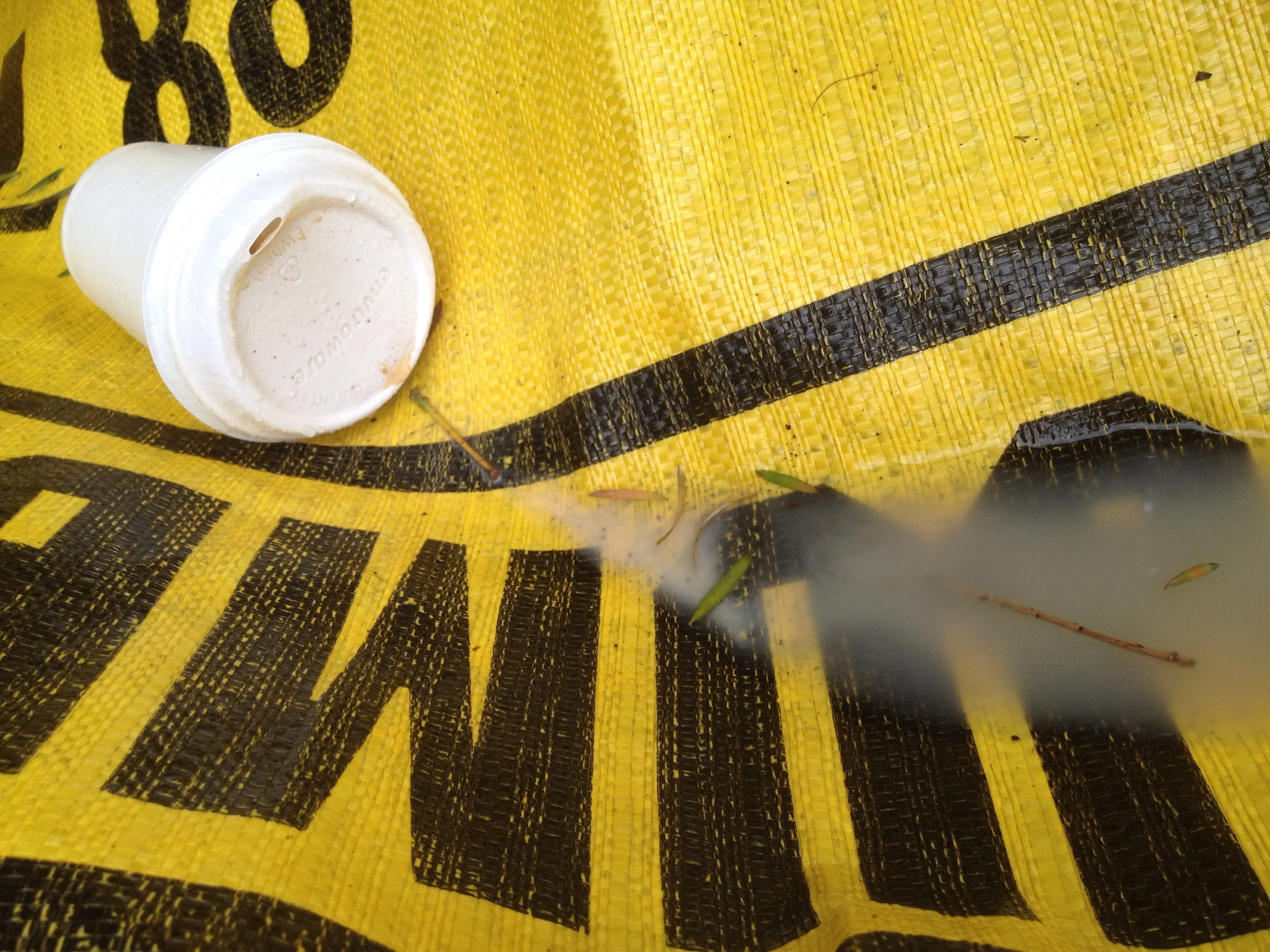 I love how this blurry intrusion of the spill interipts the very definite forms and technical environment created by the lettering and the almost pixelated effect of the textile. Nothing in this image is 100% coherent and following societal rules or as it should be. The cup is tilted and discarded, now a found object. The letters don't make sense or read anything. The colours are alarmist as if to exaggerate that a bigger accident happened here than in reality, to draw your eye into trying to understand what I'm still trying to figure out - why I take these photos. The spilt mess is like a slug in the rain, almost unidentifiable. Is it tea, or coffee washed out by the rain. We don't know.