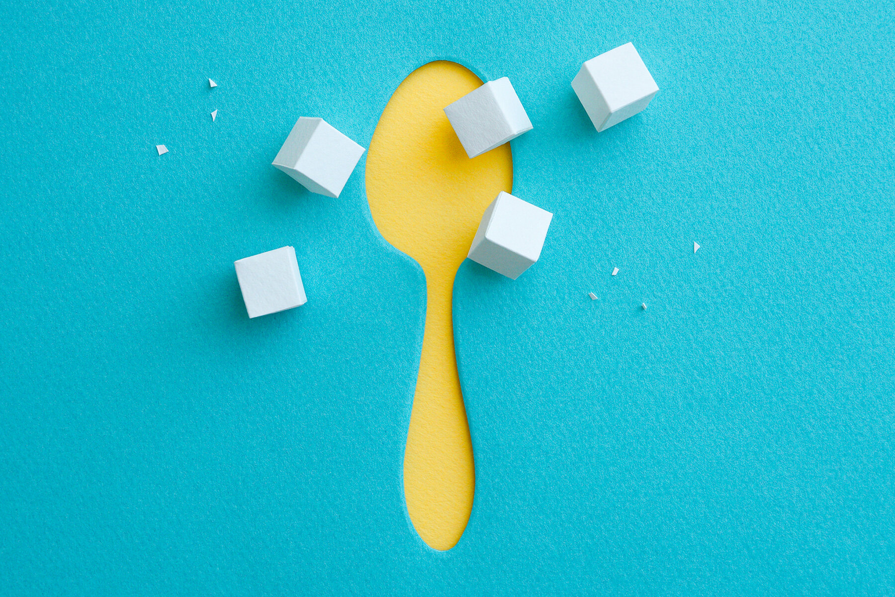 Yellow paper spoon with scattered sugar cubes